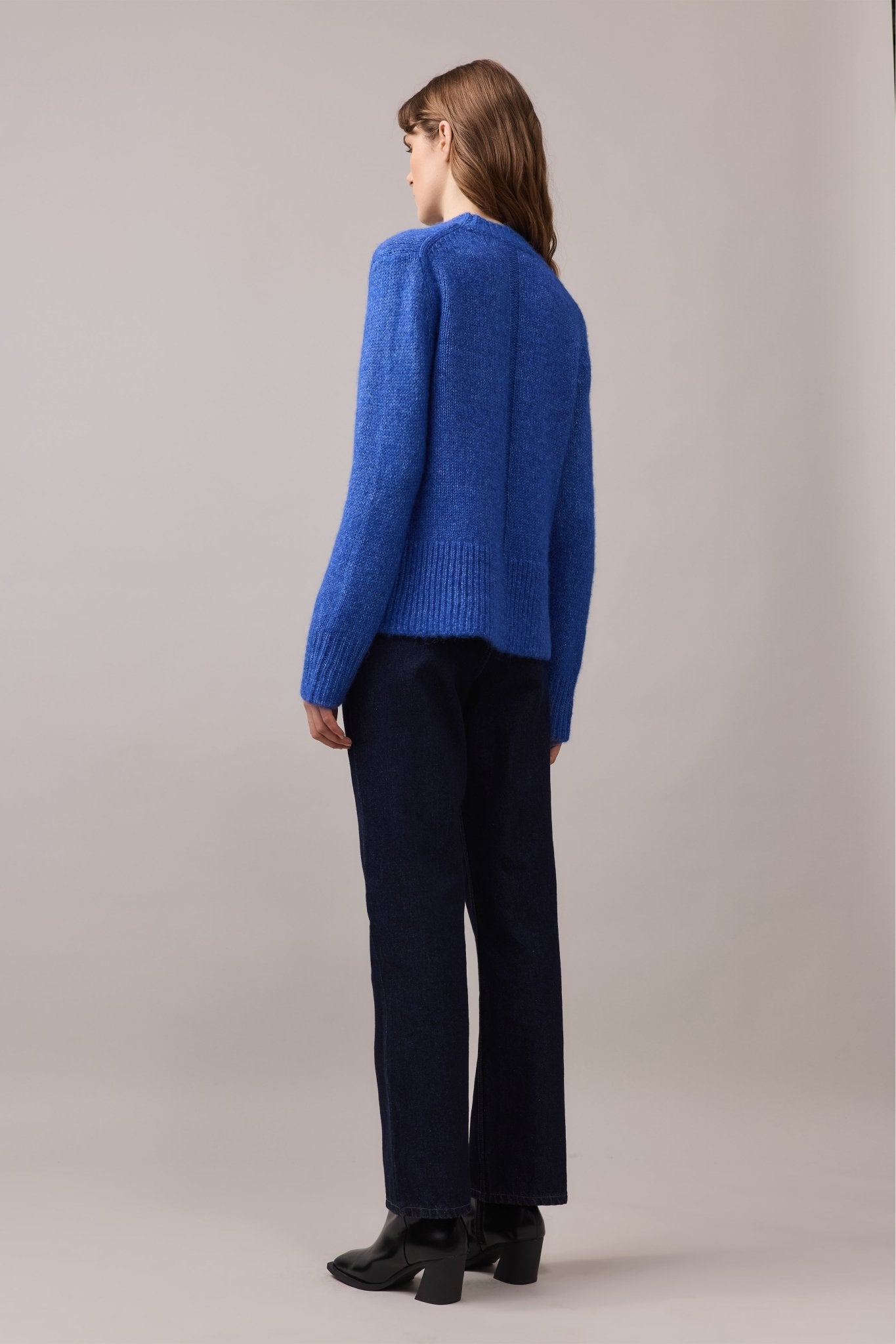 Back view of a woman wearing the Alfie Alpaca Cotton Knit in cobalt blue, showing the relaxed silhouette and centre back dropped-stitch detail.