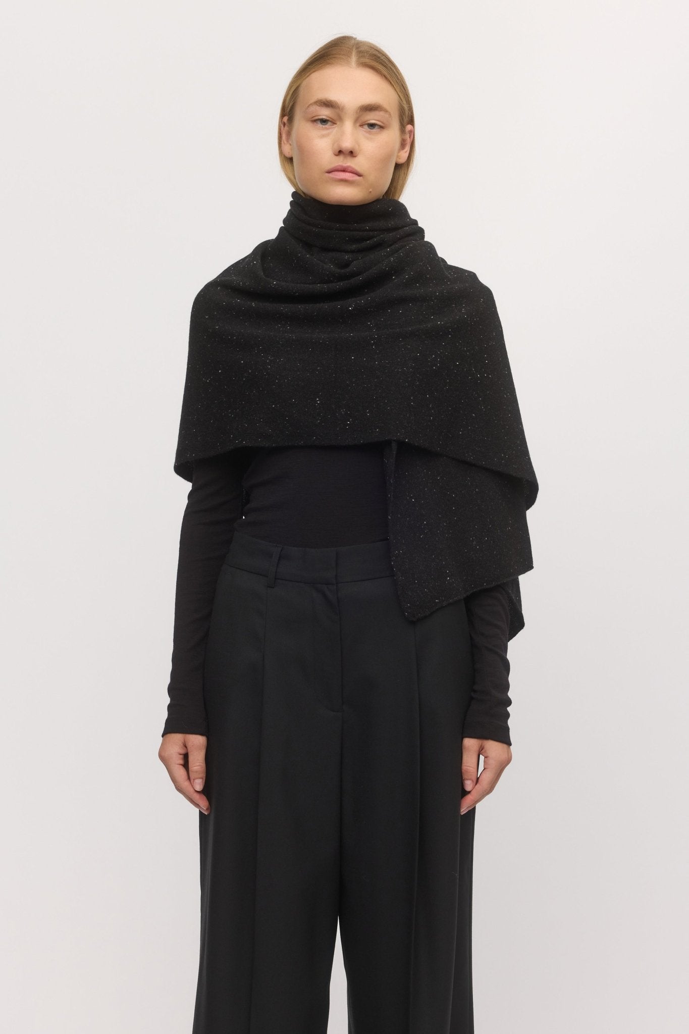 Woman wearing the Anywhere Wrap in Stargaze โ front view of wool-cashmere wrap styled over a black outfit, from Skin and Threads.