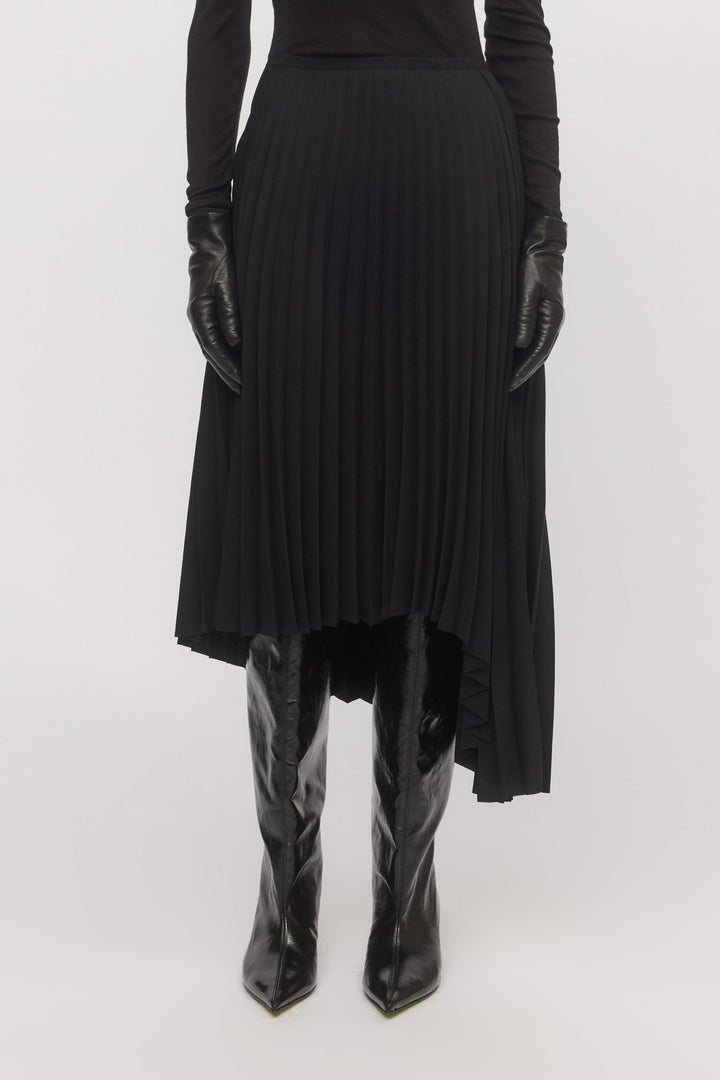 Close-up of pleated black Asymmetric Pleat Skirt, highlighting asymmetry and fabric texture.