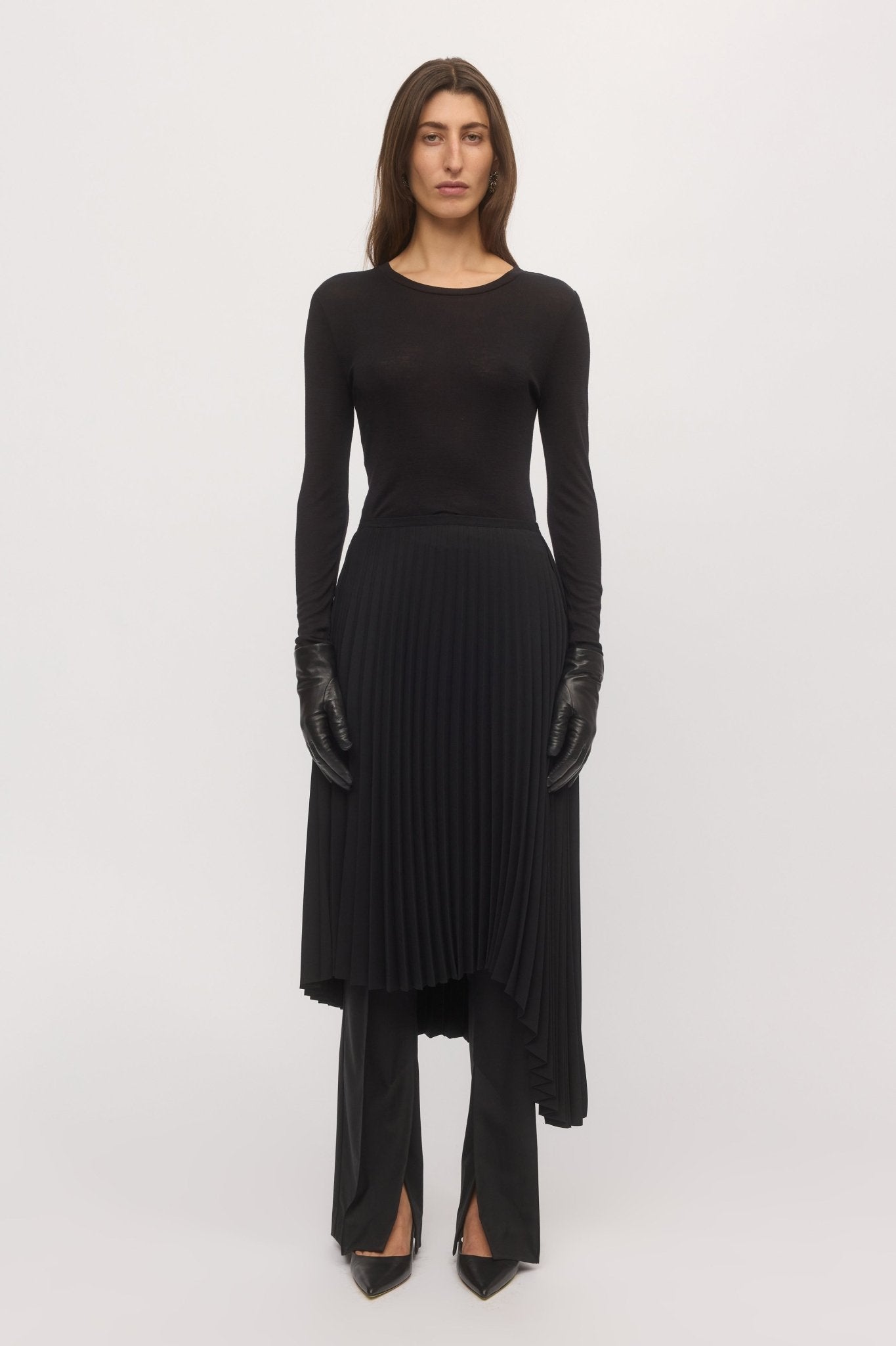 Woman wearing black Asymmetric Pleat Skirt with fitted top and knee-high boots