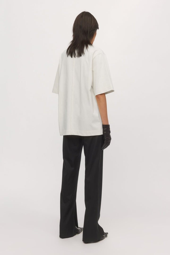 Back view of woman wearing oversized White Boyfriend Tee – straight fit with soft drape over black trousers.