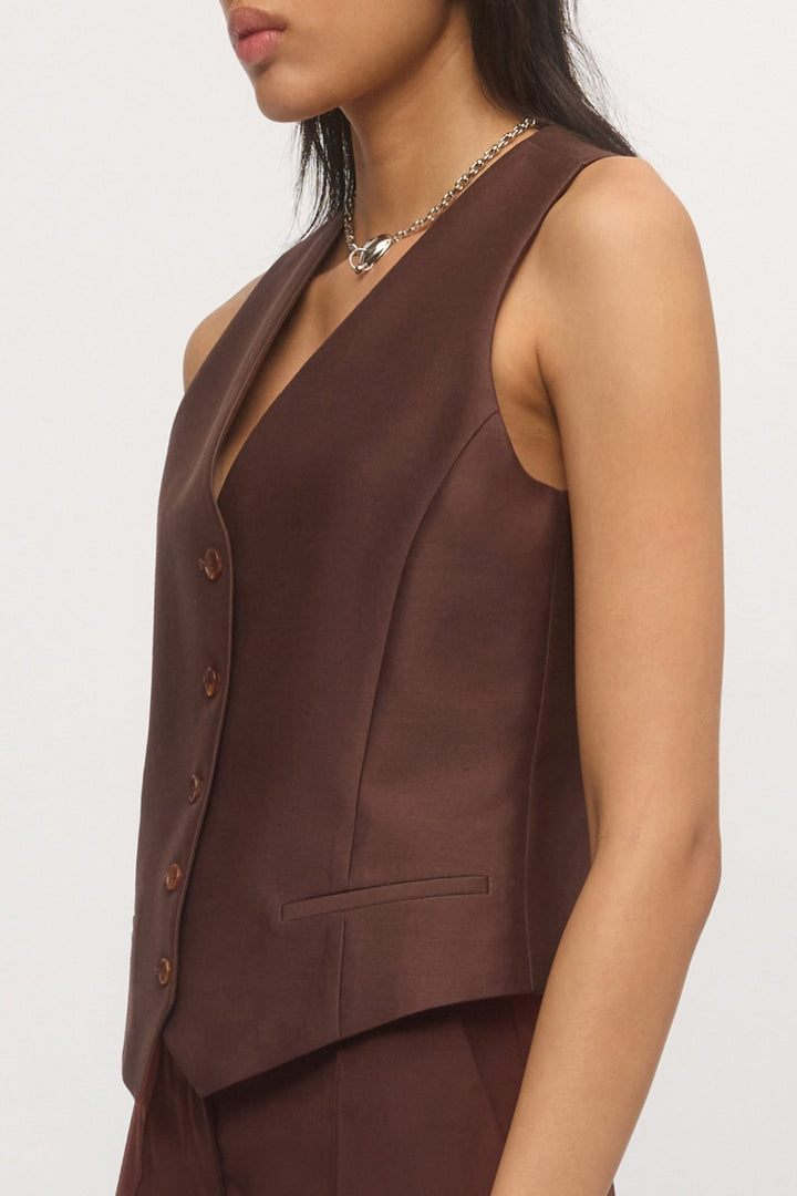 Side close-up of Button Down Vest – structured tailoring, angled hem, and soft brown fabric texture.