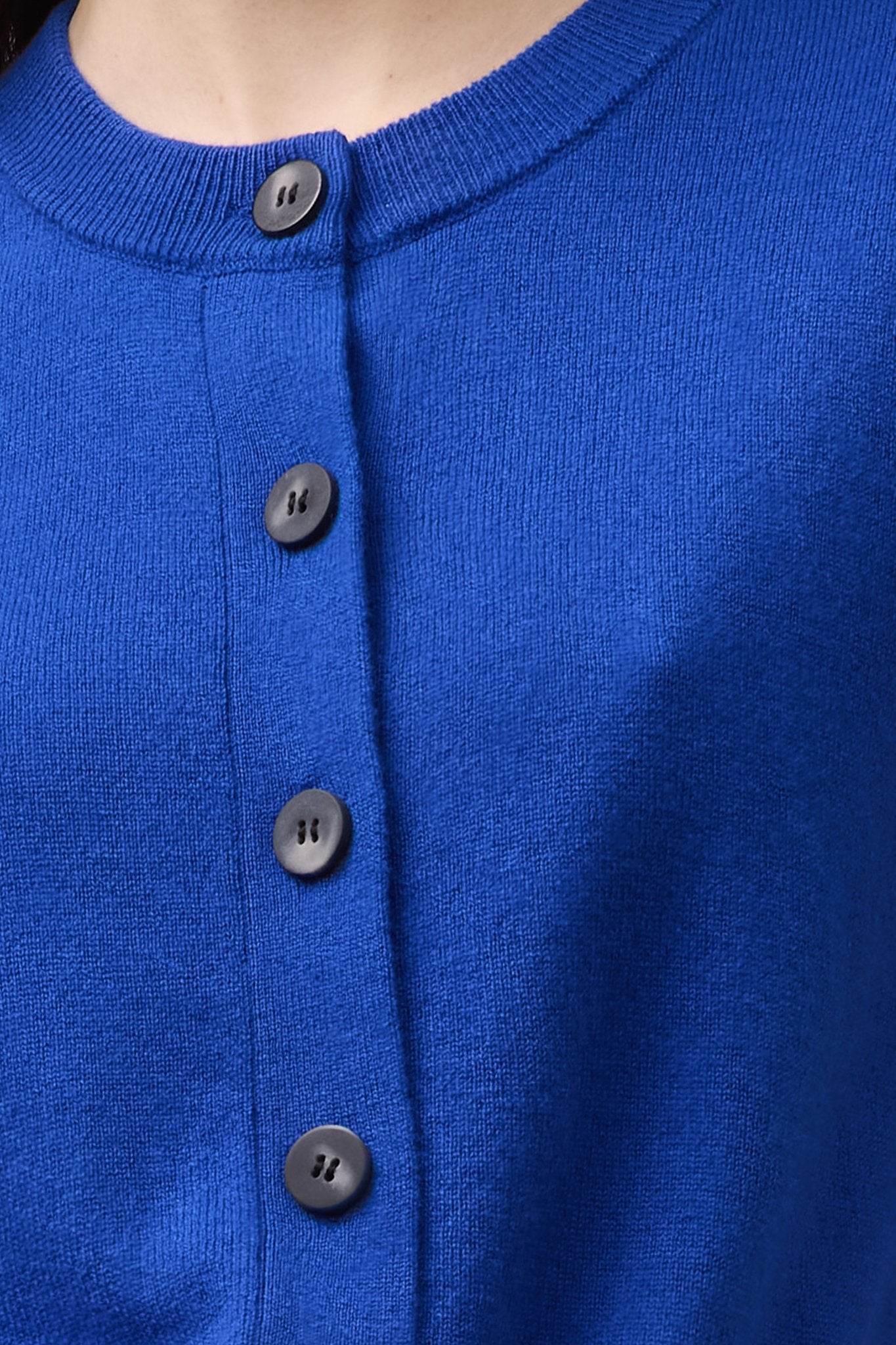 Close-up of the Cashmere Crew Neck Cardigan in cobalt blue, highlighting the ribbed neckline and mock horn button detailing in soft 100% cashmere.