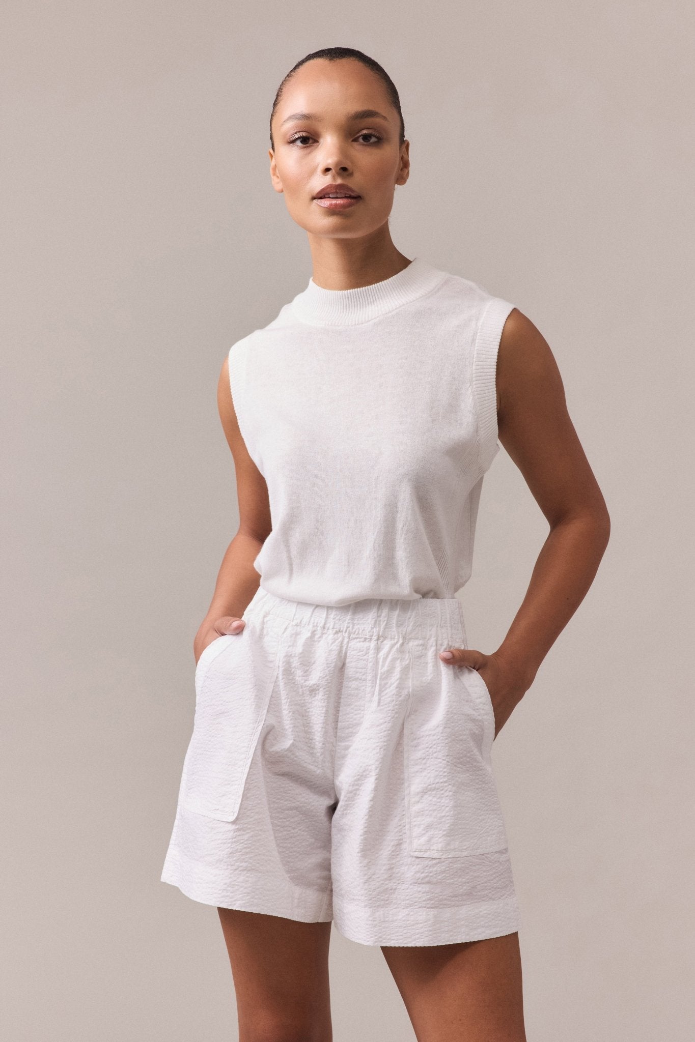 A woman is wearing a white Crawford textured cotton shorts paired with white knit top.