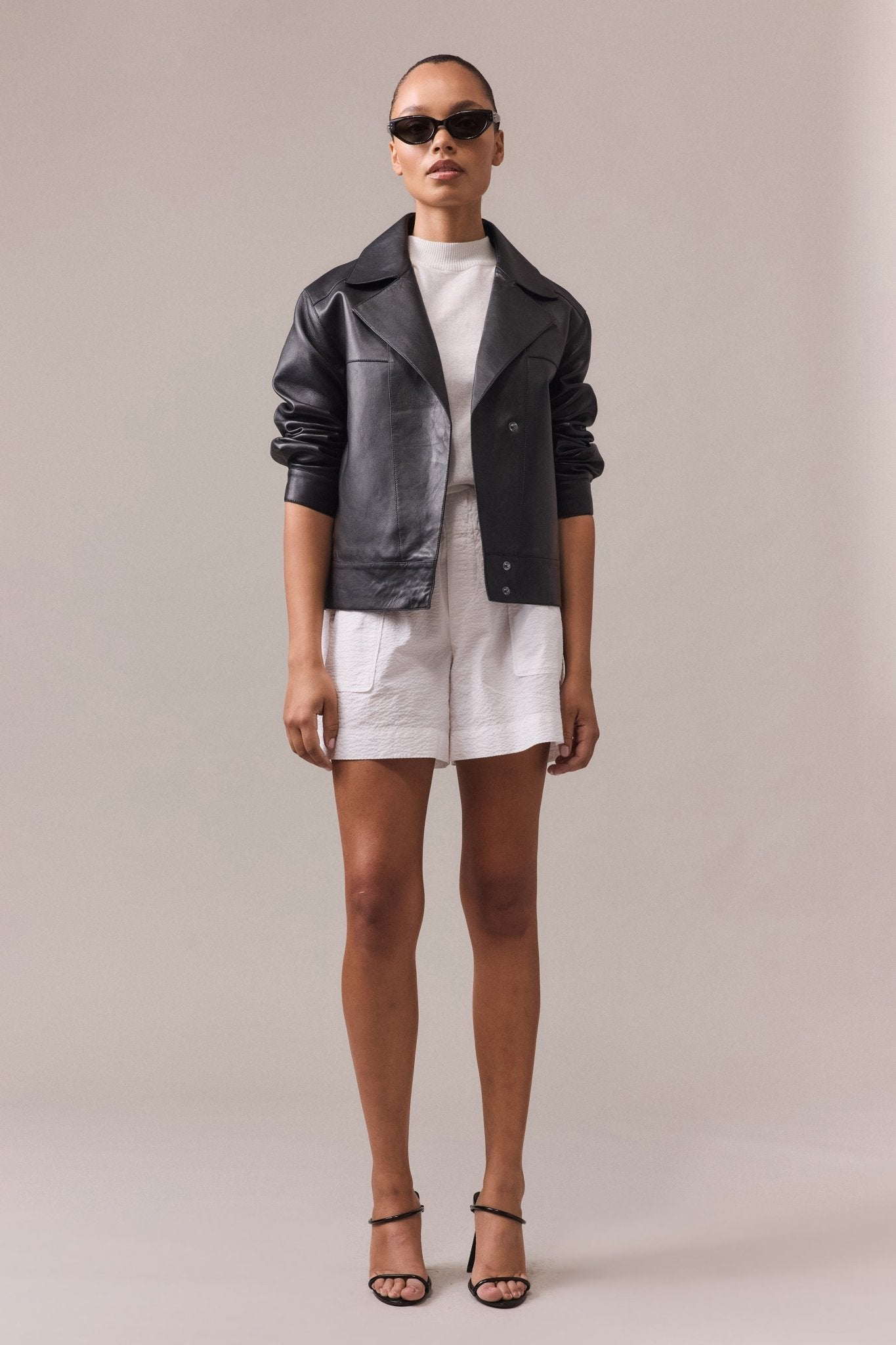 A woman is wearing Crawford textured cotton short paired with black leather jacket and white top.