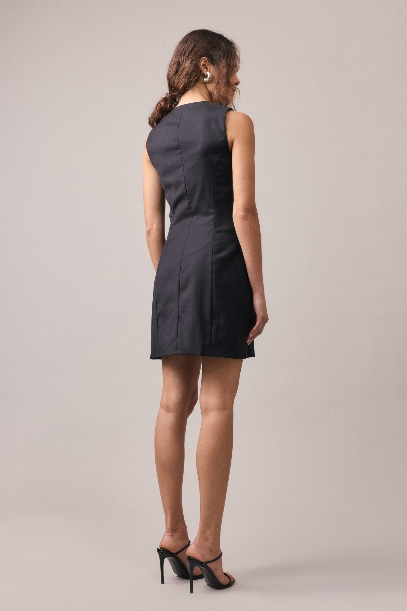 The Havana Tailored Dress in black, seen from behind, highlighting its structured fit, seamless dart seams, and tailored jet pockets for a refined, minimalist silhouette.