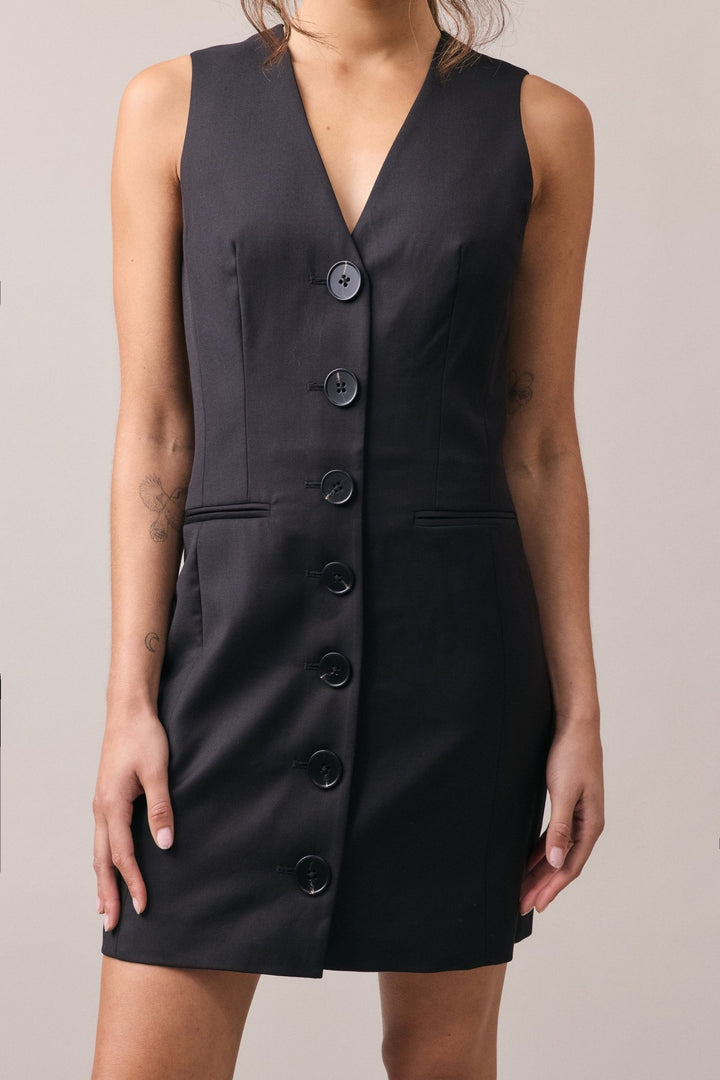 A woman in the Havana Tailored Dress, with focus on the deep V-neckline, structured silhouette, and lightweight wool fabric.