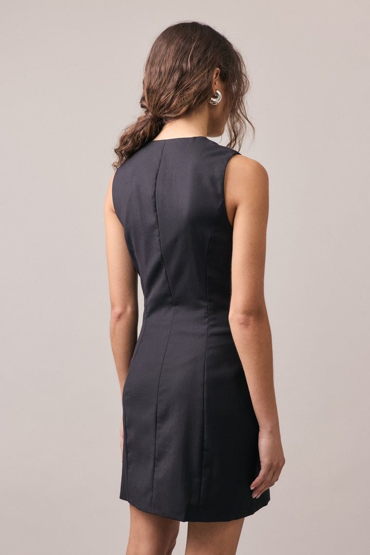 A woman wearing the Havana Tailored Dress in black, highlighting the fitted shape and minimalist elegance from behind.