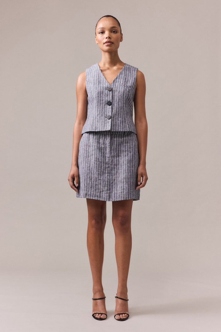 A woman wearing a black striped linen A-line skirt paired with a matching linen vest.