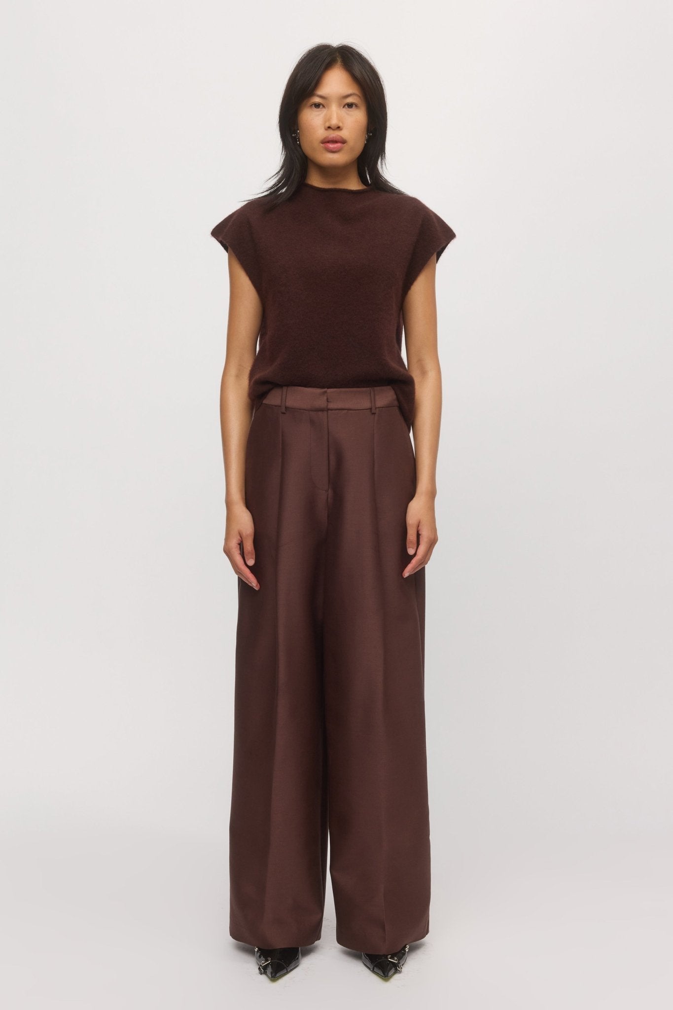 A woman is wearing knit tank in mahogany paired with wide-leg pants.