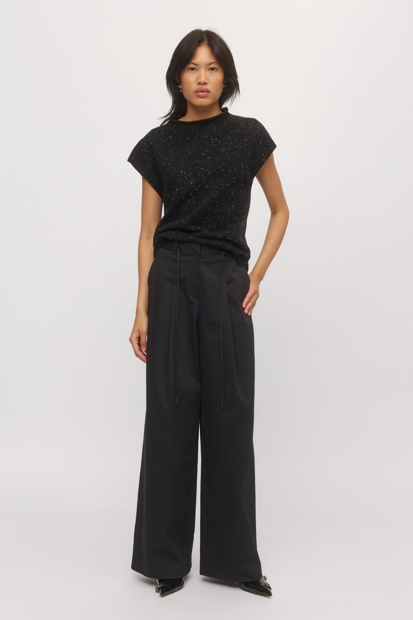 A woman is wearing a knit tank with cap sleeves paired with wide-leg pants.