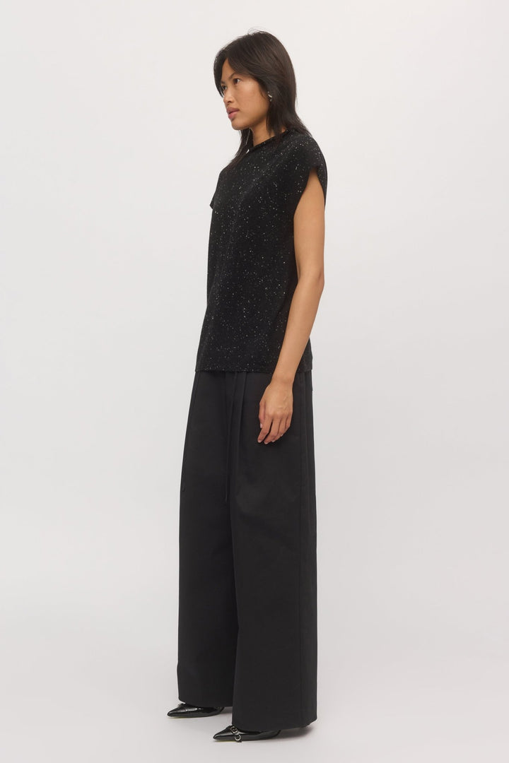Side view of a woman wearing a knit tank top with wide-leg pants.