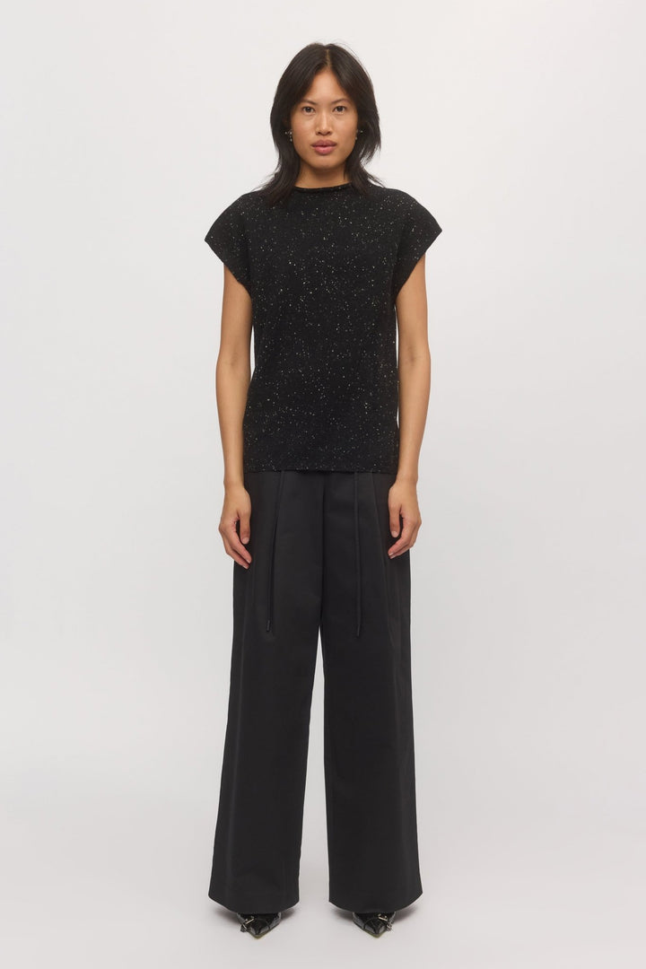 A woman is wearing a knit tank top with wide-leg pants.