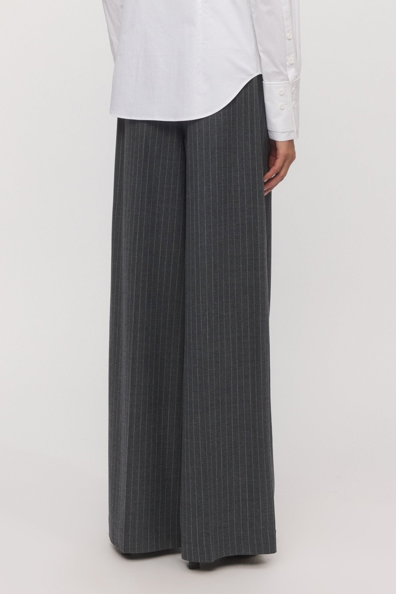 Back view of a woman wearing graphite pinstripe Lola Wide Leg Pants, styled with a crisp white shirt. - Skin and Threads