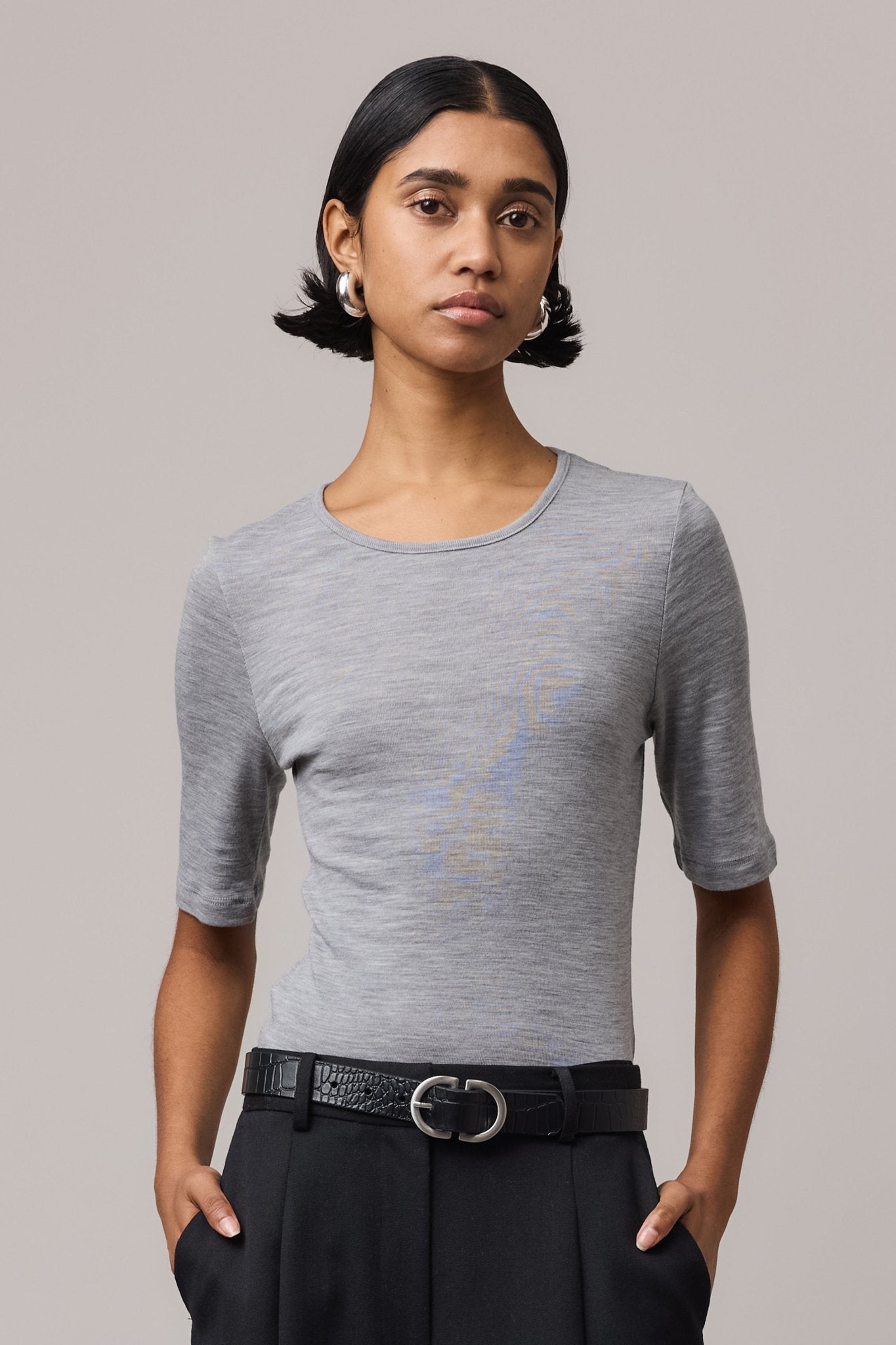 Close-up of a woman wearing a grey Merino Wool Crew Neck Tee with elbow sleeve.
