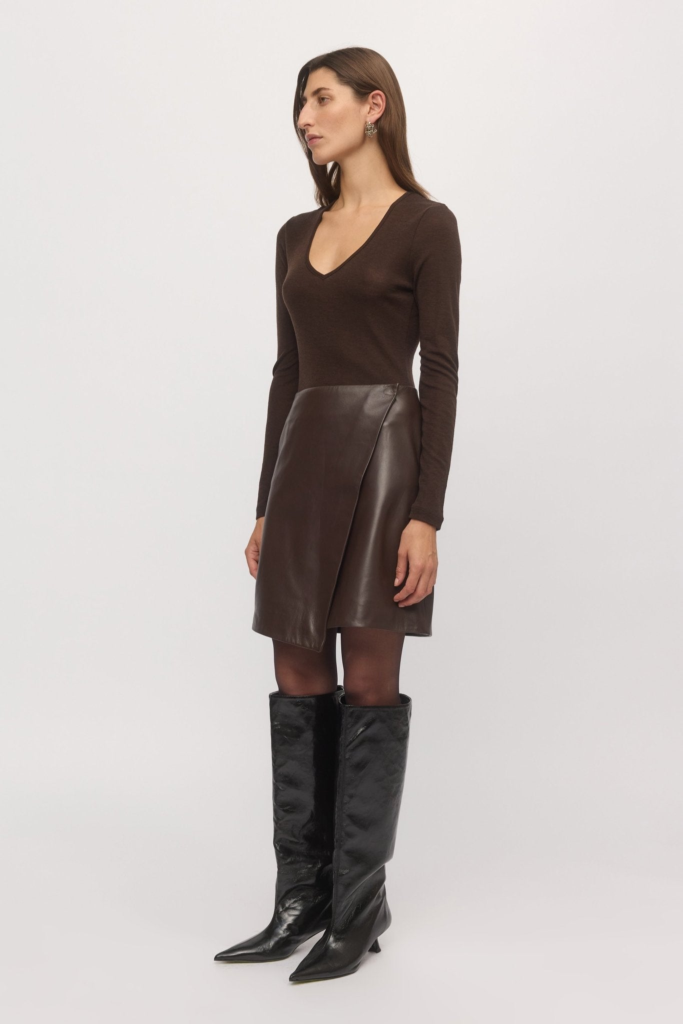 Side view of mahogany Merino V-neck sweater styled with brown leather skirt – Skin and Threads