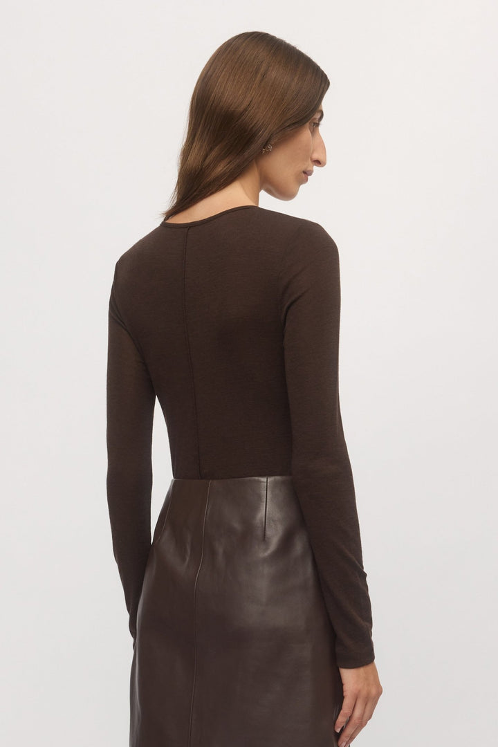 Close-up back view of woman wearing Merino V sweater in mahogany wool with brown leather mini skirt – Skin and Threads