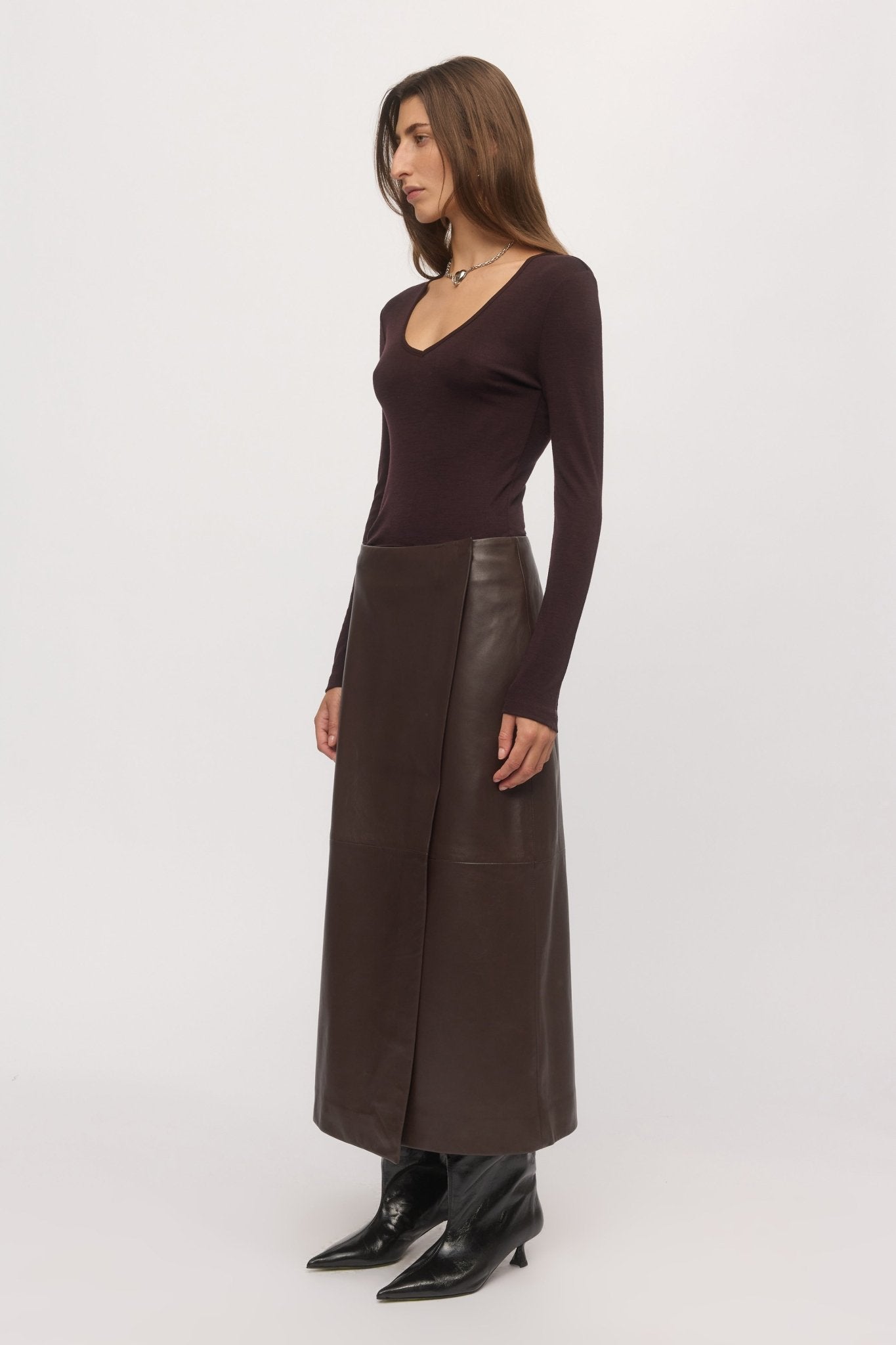 Side view of woman in plum Merino V sweater and leather skirt โ Skin and Threads