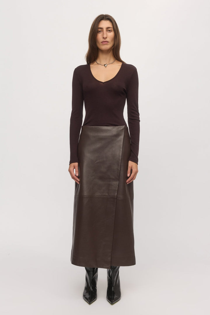 Front view of woman wearing plum Merino V-neck sweater with leather skirt โ Skin and Threads