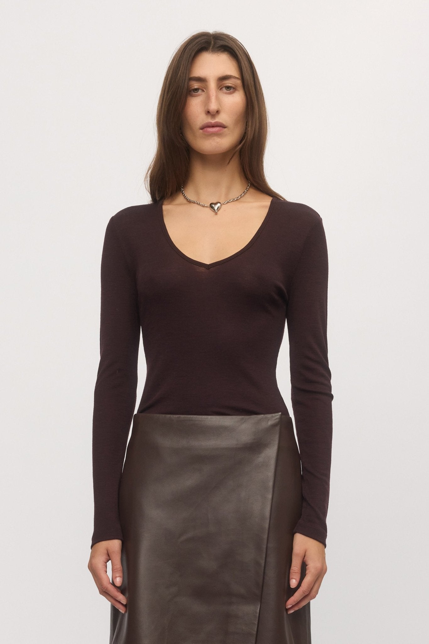 Front close-up of plum Merino V-neck sweater worn with leather skirt โ Skin and Threads
