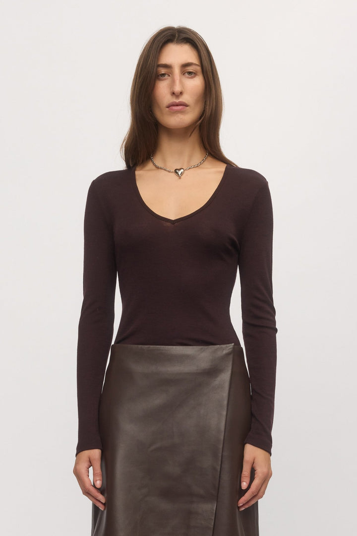 Front close-up of plum Merino V-neck sweater worn with leather skirt โ Skin and Threads