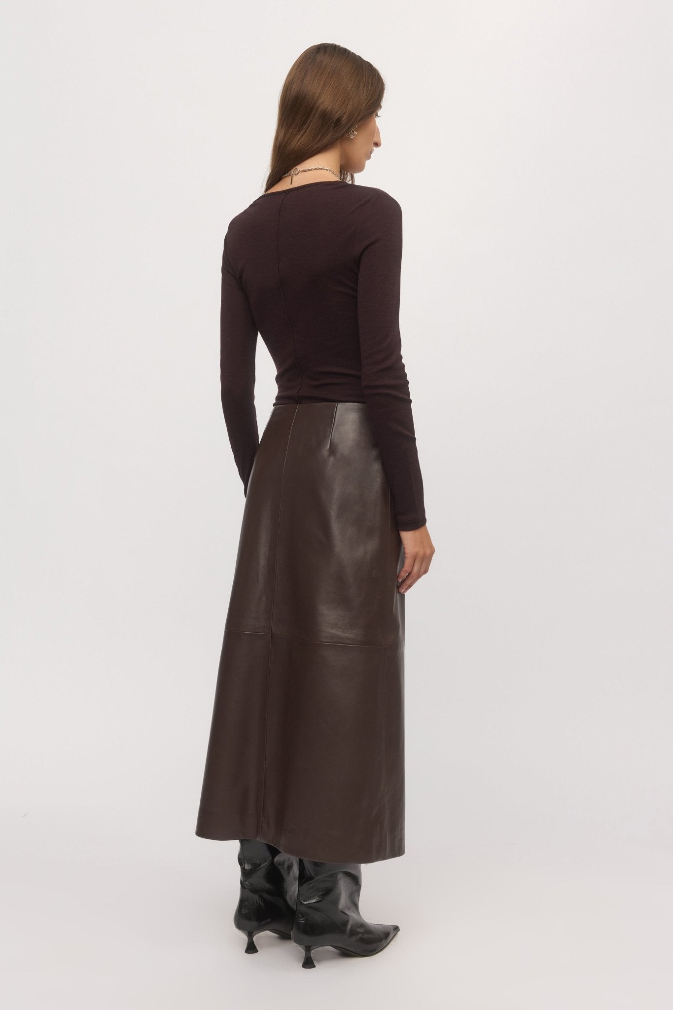 Back view of woman wearing Merino V plum wool sweater and leather skirt โ Skin and Threads