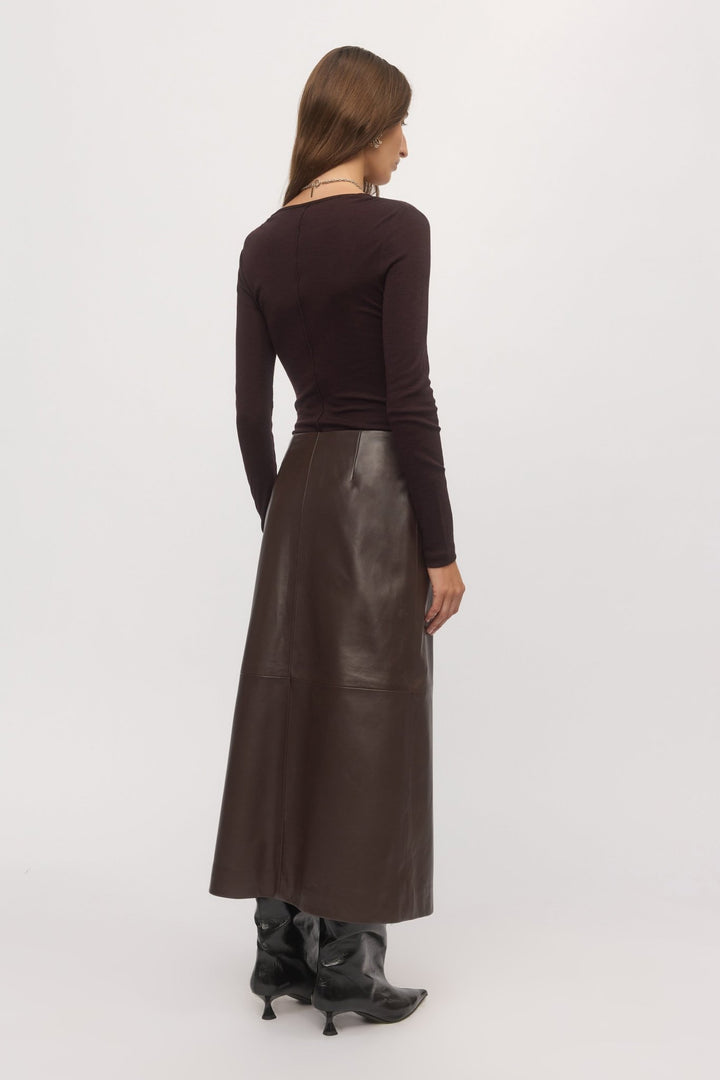 Back view of woman wearing Merino V plum wool sweater and leather skirt โ Skin and Threads
