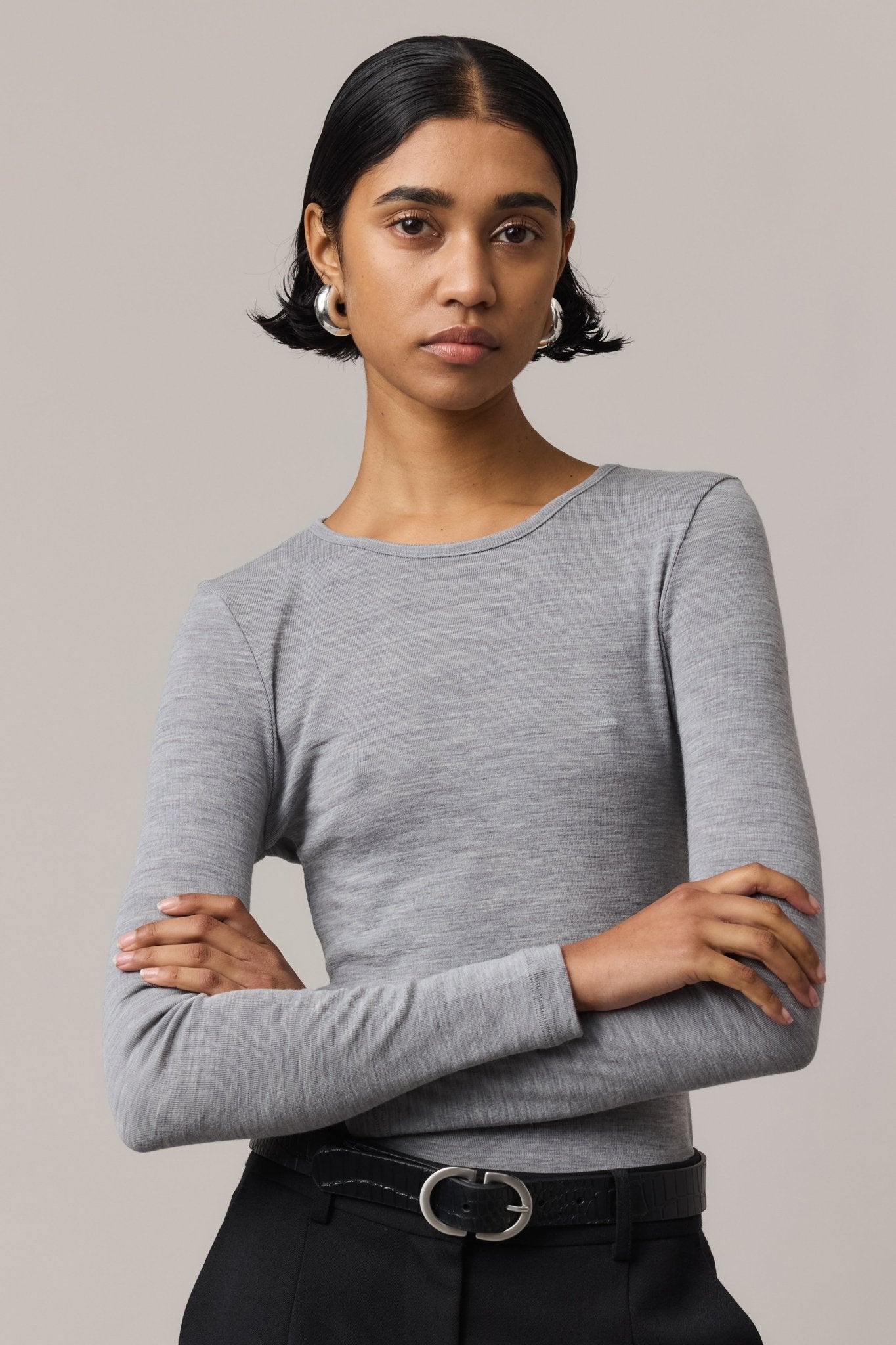 Close-up of a woman wearing a long-sleeve Merino Wool Crew Neck with crossed arms, paired with black linen pants.