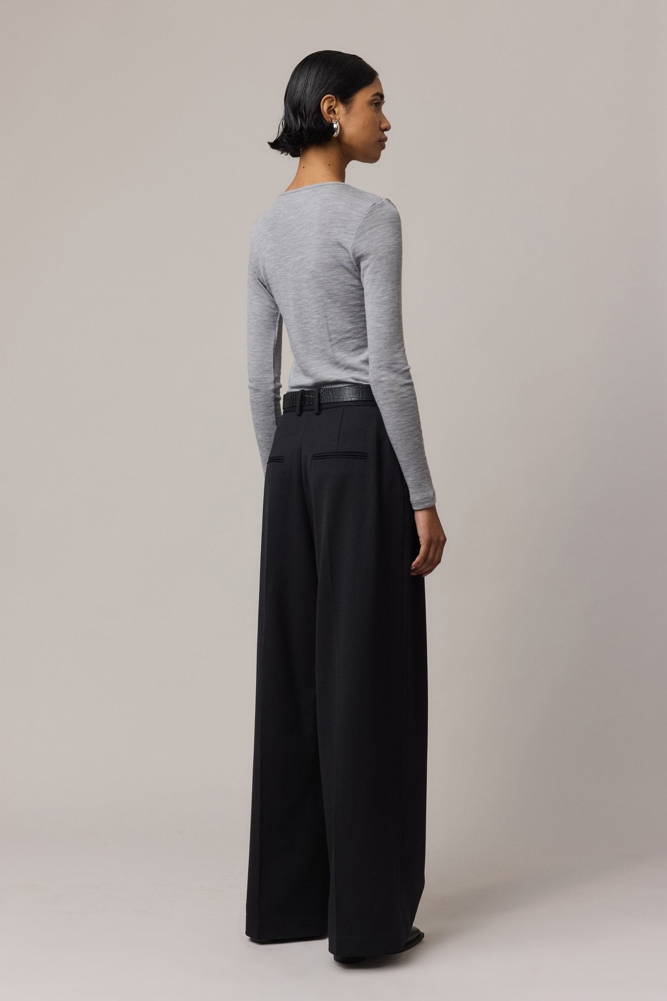 Back view of a woman wearing a long-sleeve Merino Wool Crew Neck with black linen pants.
