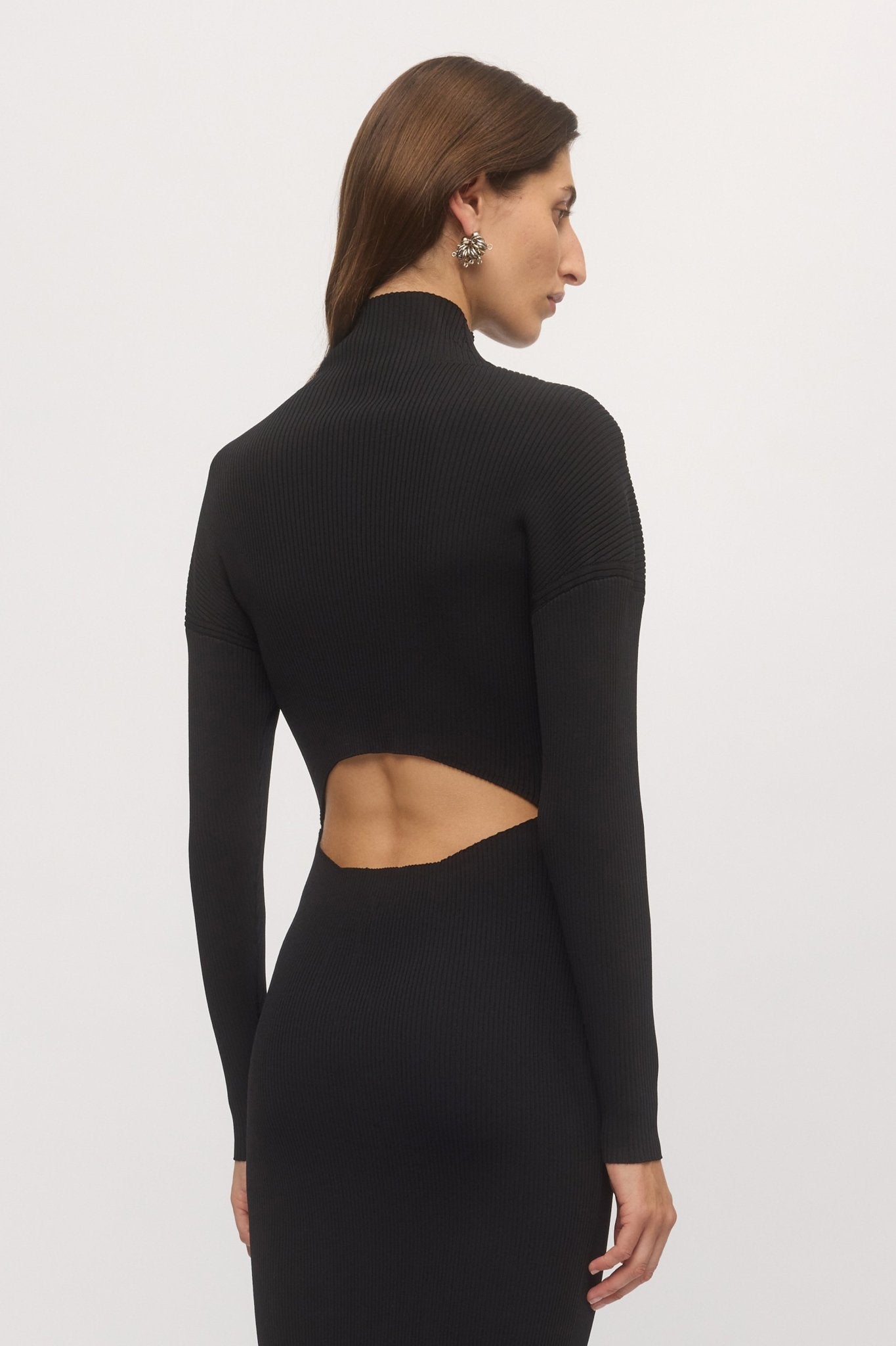Close-up back view of woman wearing black Open Back Rib Dress, showing sculpted ribbed knit fit and curved open back cut-out โ Skin and Threads