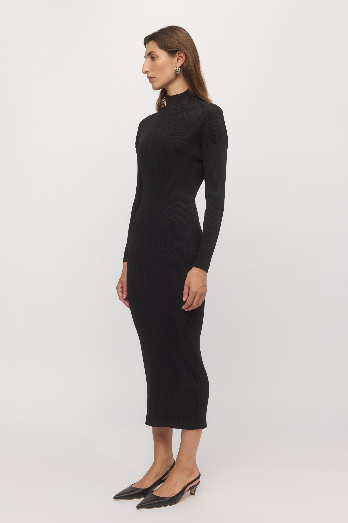 Side view of black ribbed midi dress with high neck and long sleeves styled with heels โ Skin and Threads