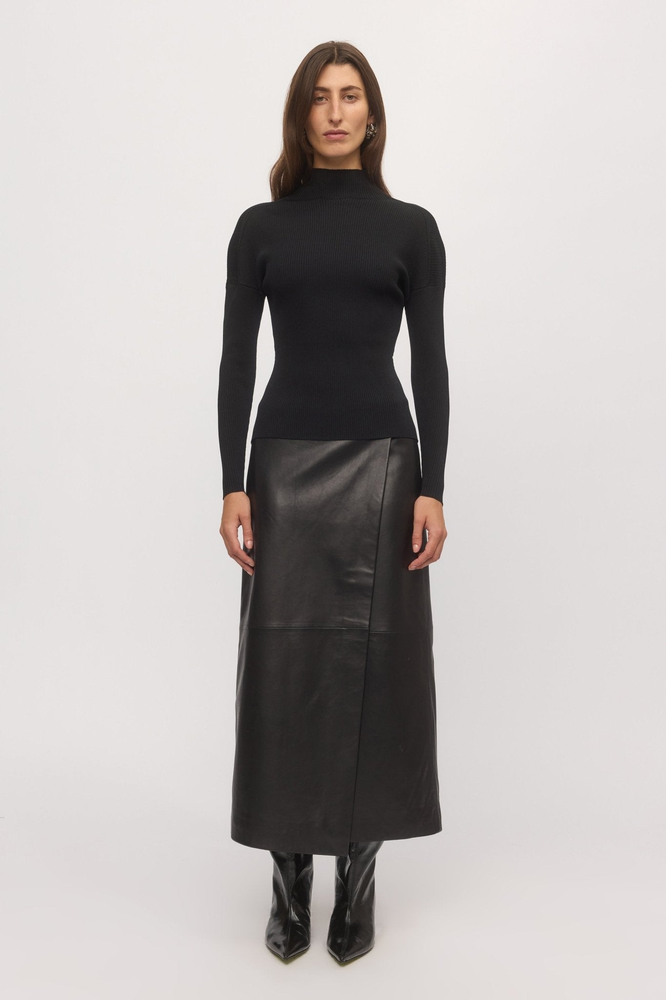 Front view of woman wearing Open Back Rib Top in black rib knit with high neckline and slim fit, styled with black leather skirt – Skin and Threads