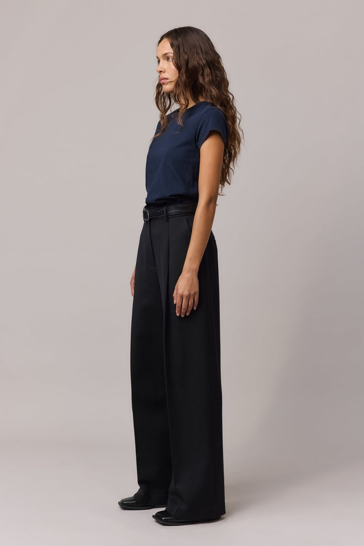 Side view of the woman in the indigo t-shirt and black trousers, showing the relaxed fit.