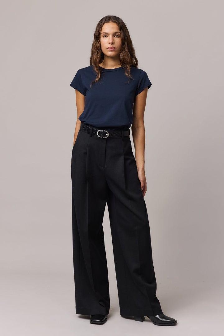 Full-body view of the woman wearing the indigo organic cotton girlfriend tee and wide-leg black trousers.