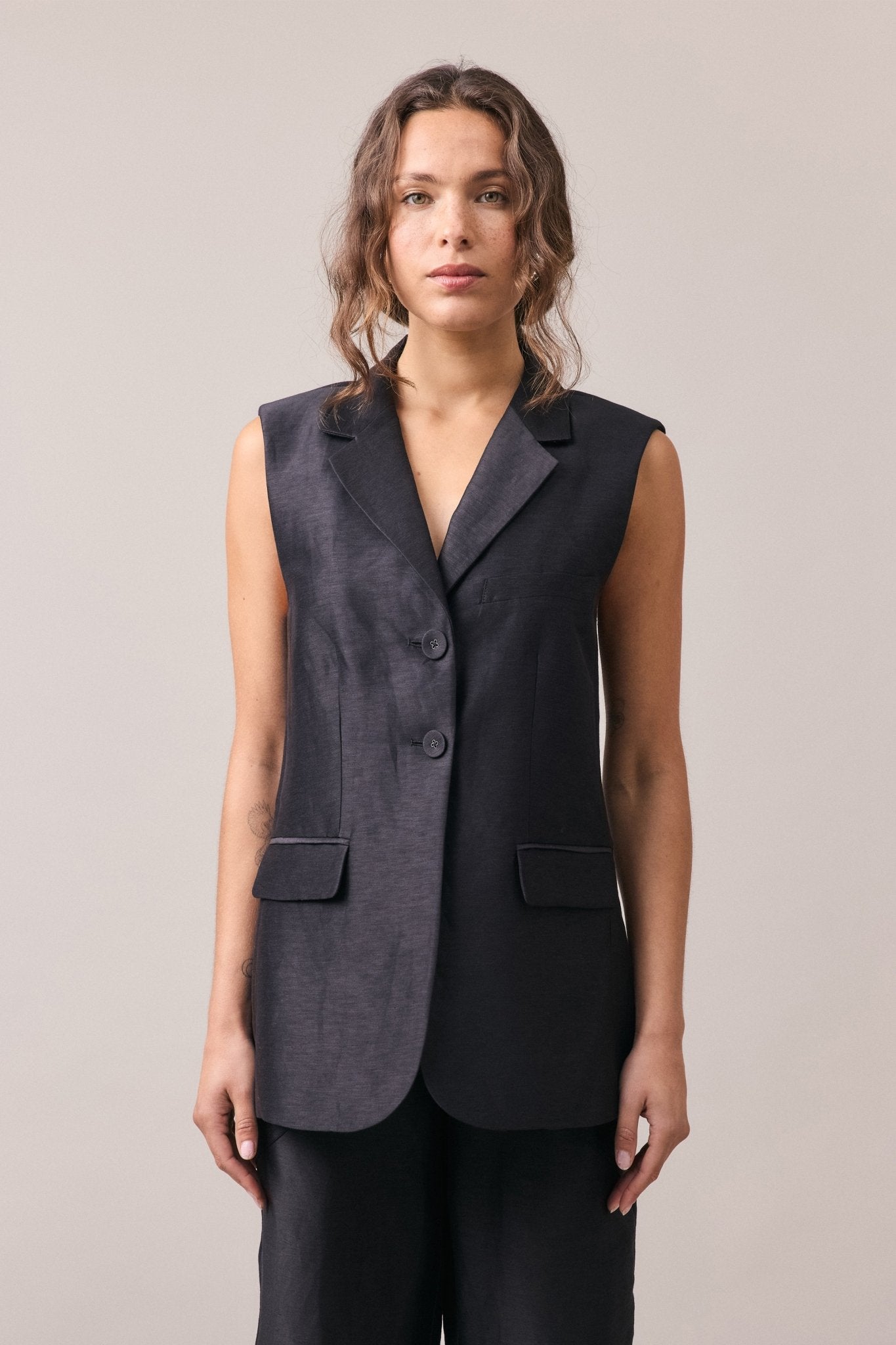 Woman wearing the Remi Silk Linen Vest with matching pants, featuring a longline profile, tailored fit, and visible double button closure.