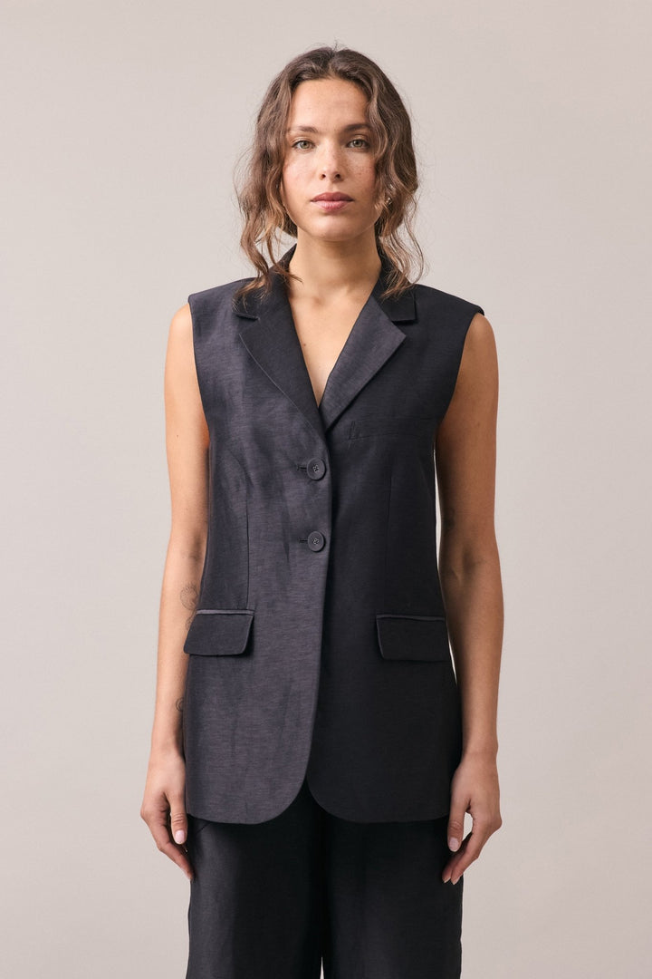 Woman wearing the Remi Silk Linen Vest with matching pants, featuring a longline profile, tailored fit, and visible double button closure.
