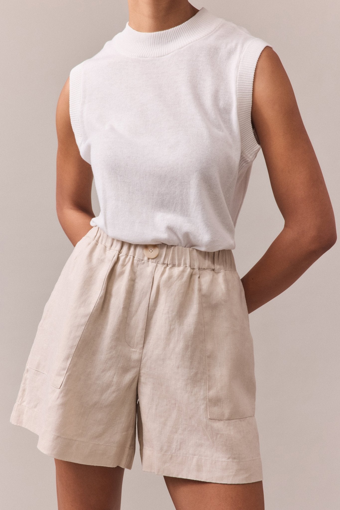 Close-up of sand Soma linen shorts with an elasticated waist, styled with a sleeveless white top.