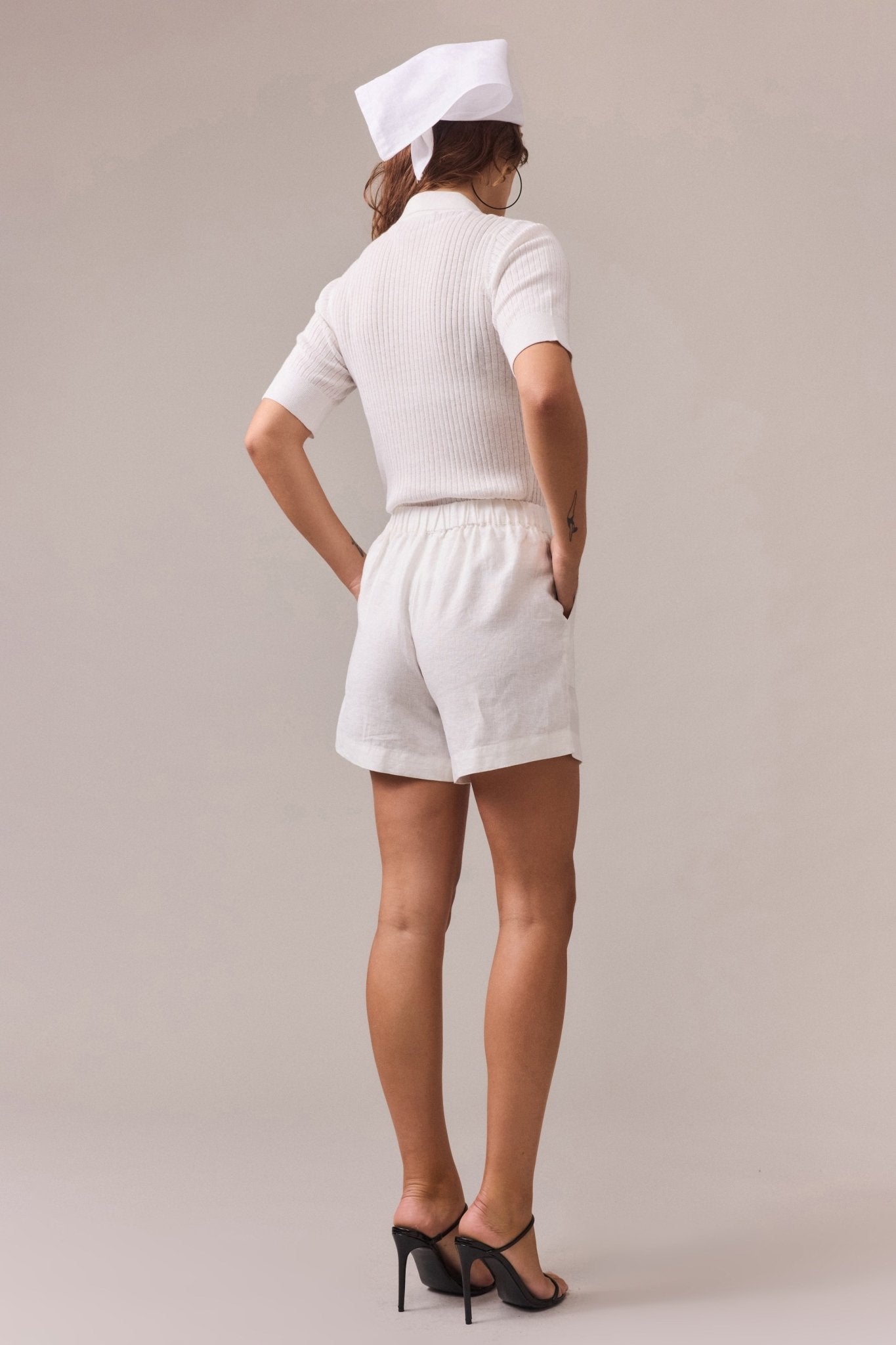Back view of the white linen shorts, displaying the elastic waistband and smooth drape of the fabric.