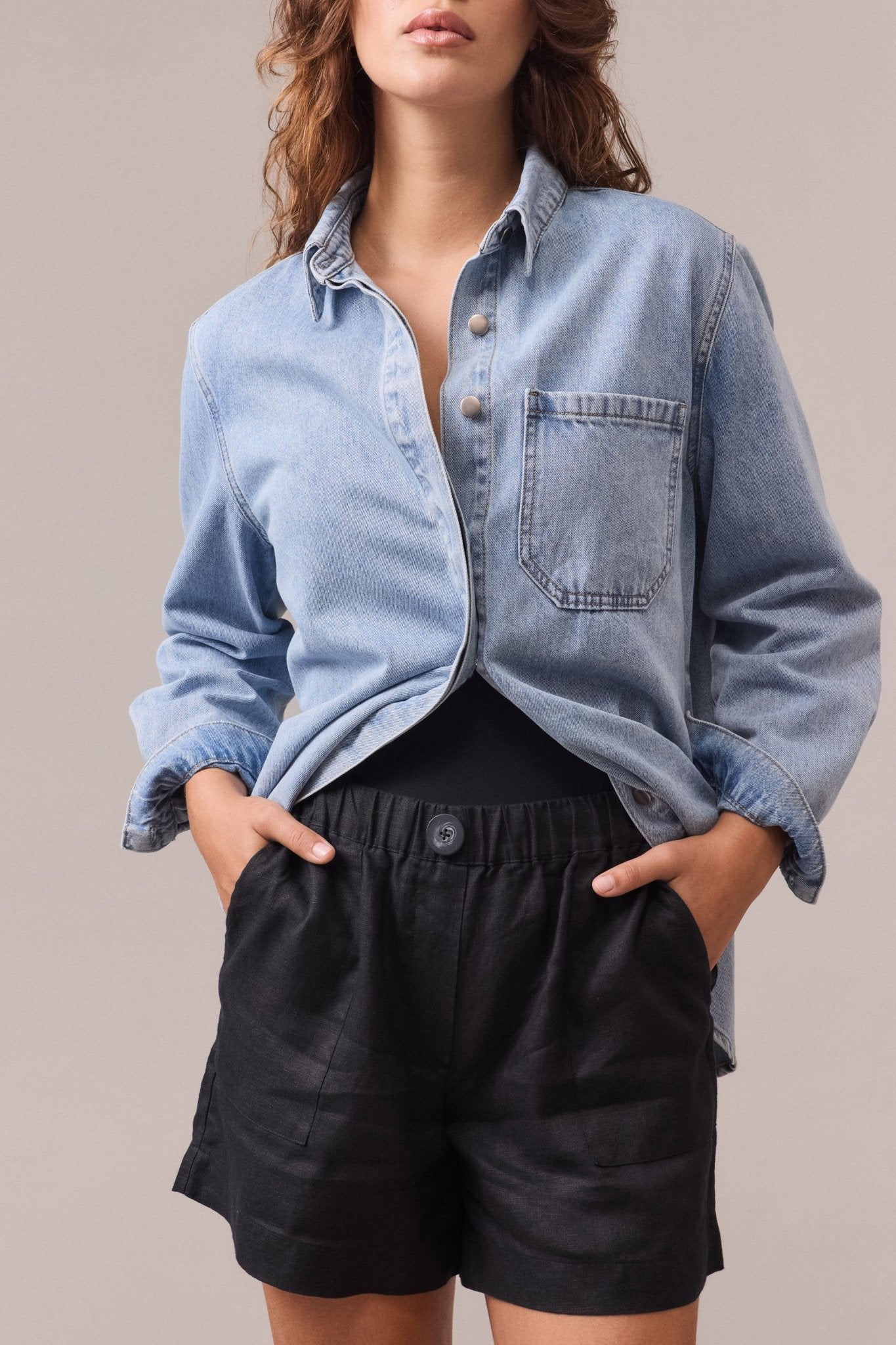 Women's black Soma linen shorts with front pockets paired with a blue denim shirt.
