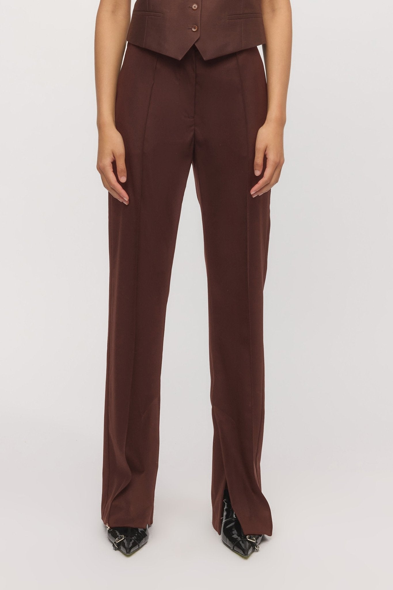 Close-up front view showing tailored waistband and pintuck seam on mahogany trousers โ Skin and Threads