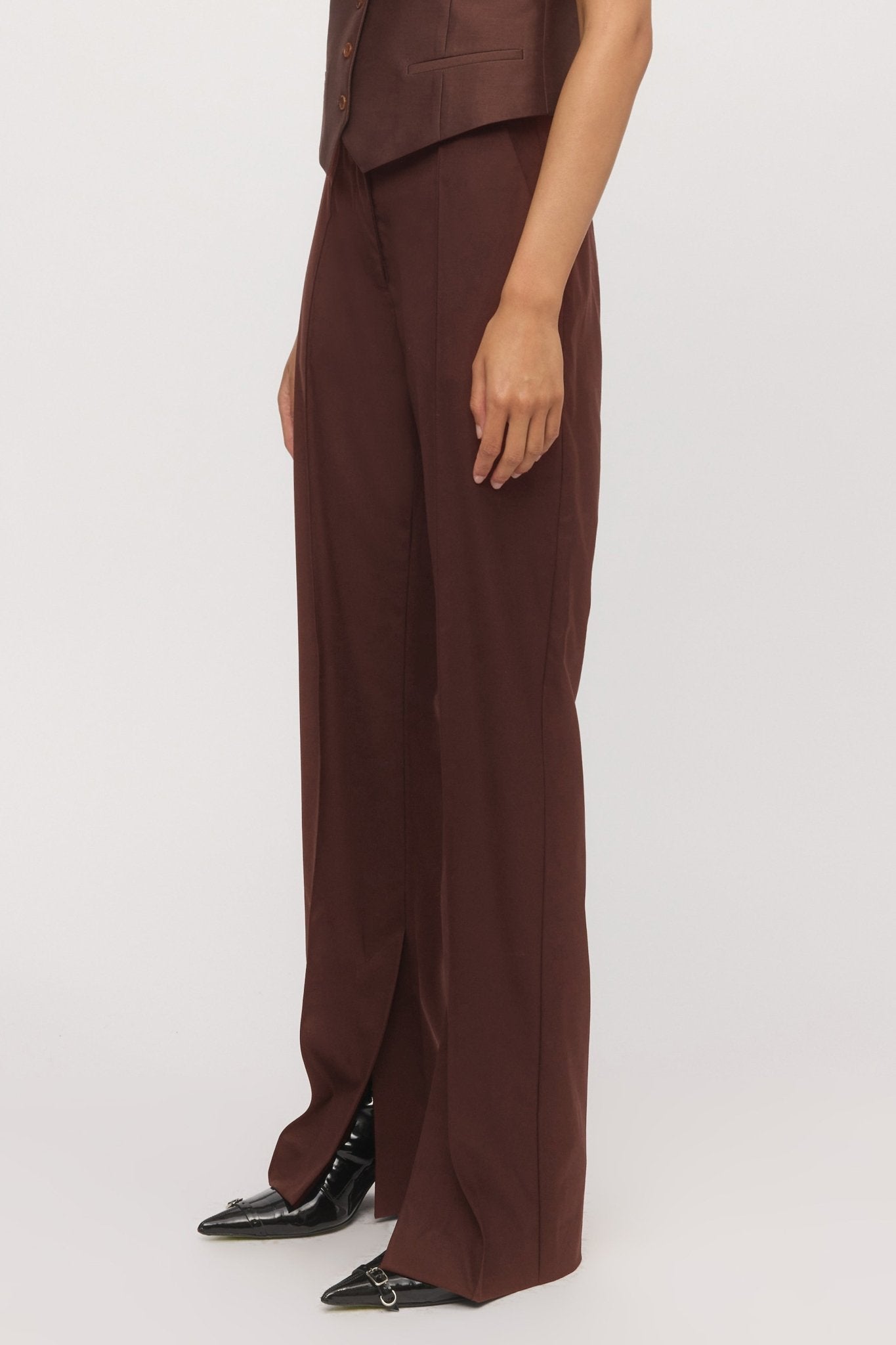 Close-up side view of mahogany trouser hem showing angled split-leg detail โ Skin and Threads