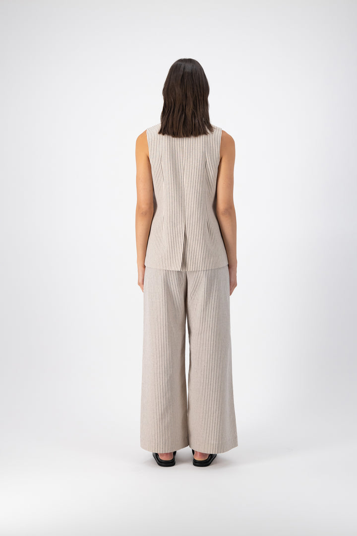 Back view of a woman wearing a Hayes Linen Stripe Vest paired with wide-leg pants in the same color. The vest is fully lined with a center back vent.
