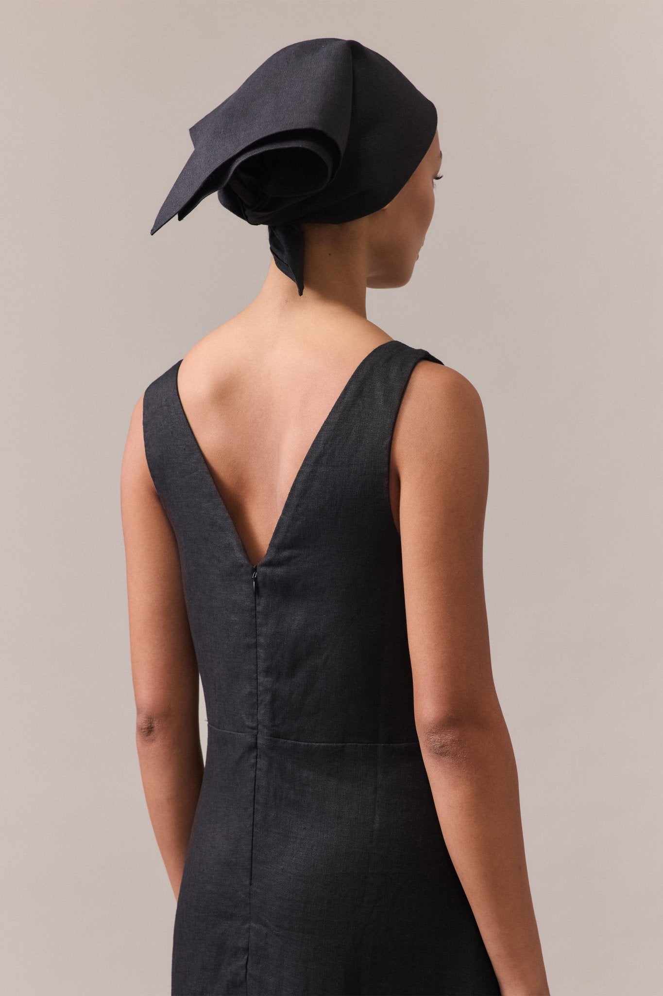 A close-up of the back of a woman wearing a black linen dress.