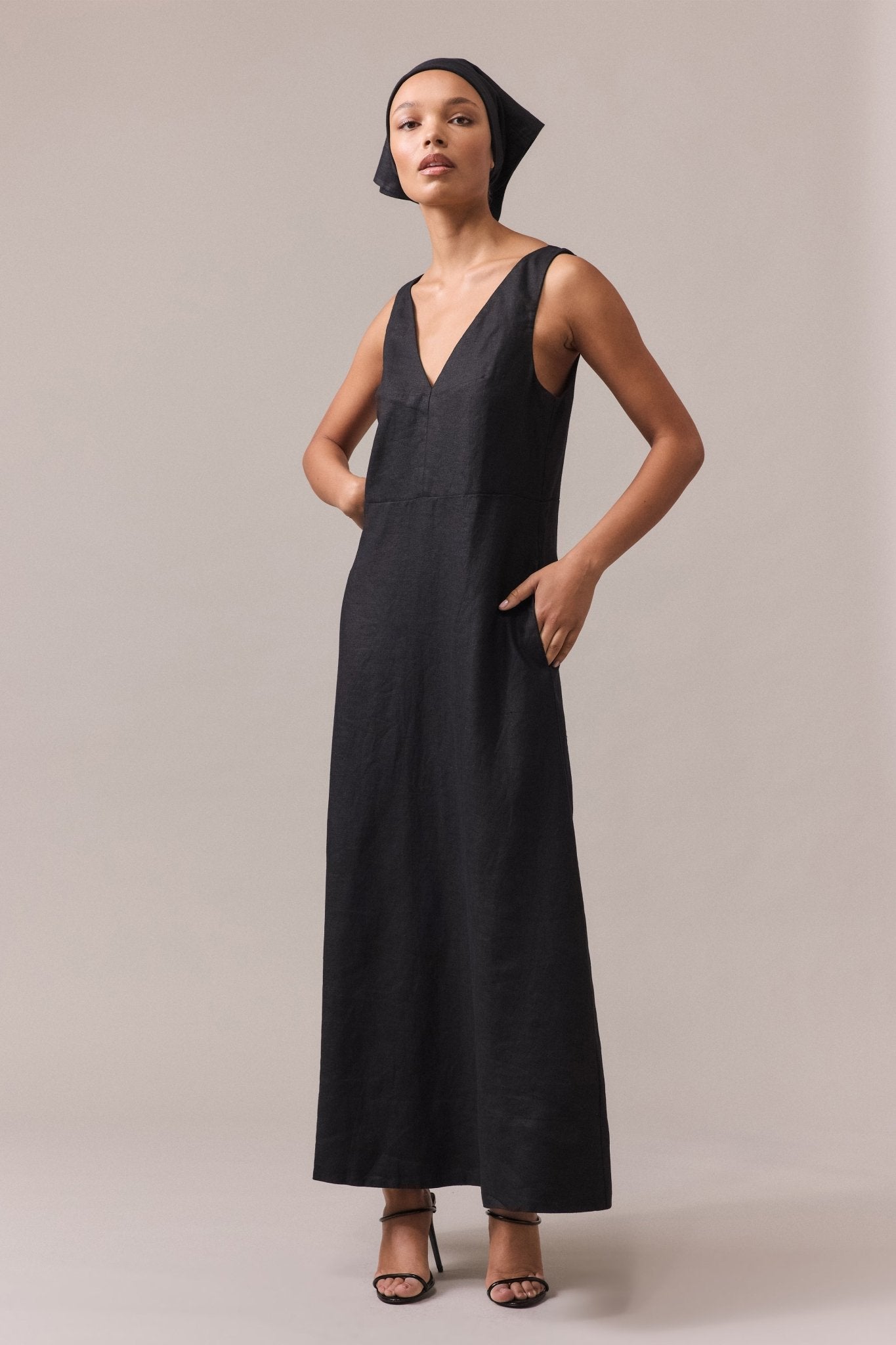 Woman wearing the black Alessandra Linen Maxi Dress with one hand in the pocket, paired with black sandals.