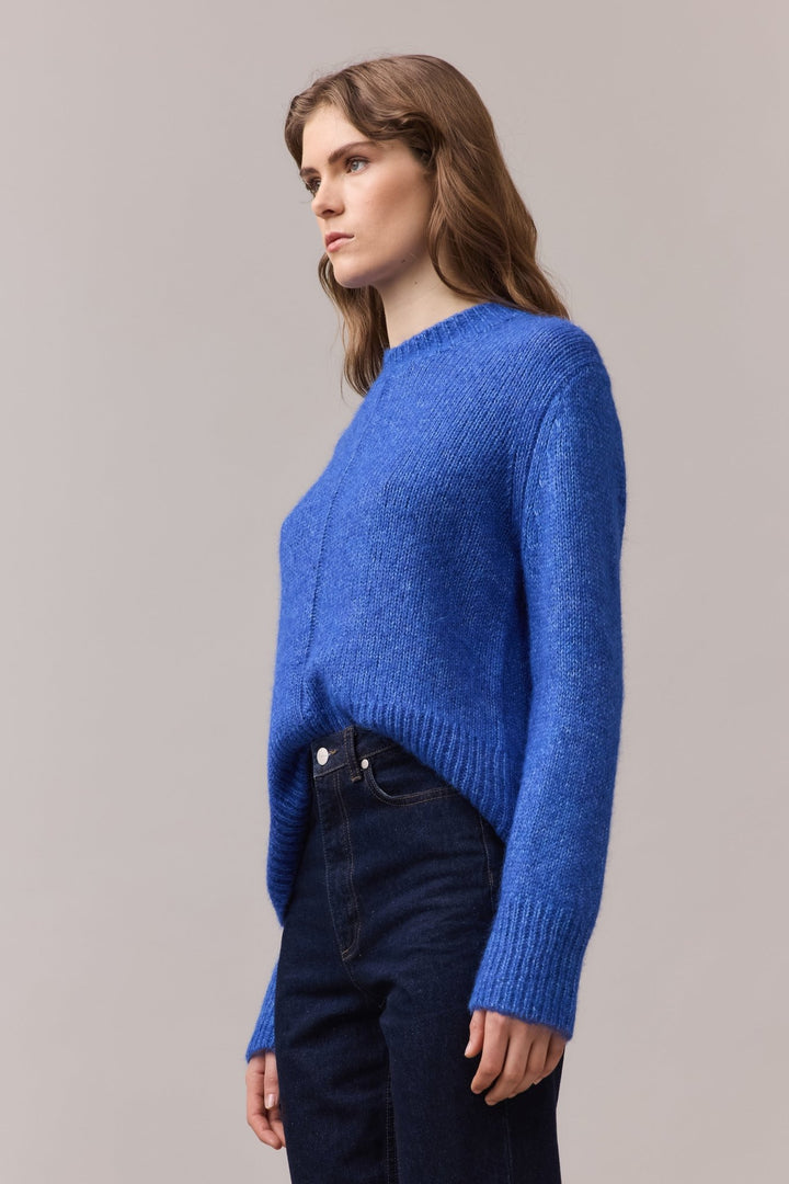 Side view of a woman in the Alfie Knit with front-tuck styling, showing the lofty alpaca-cotton texture and relaxed sleeve shape.