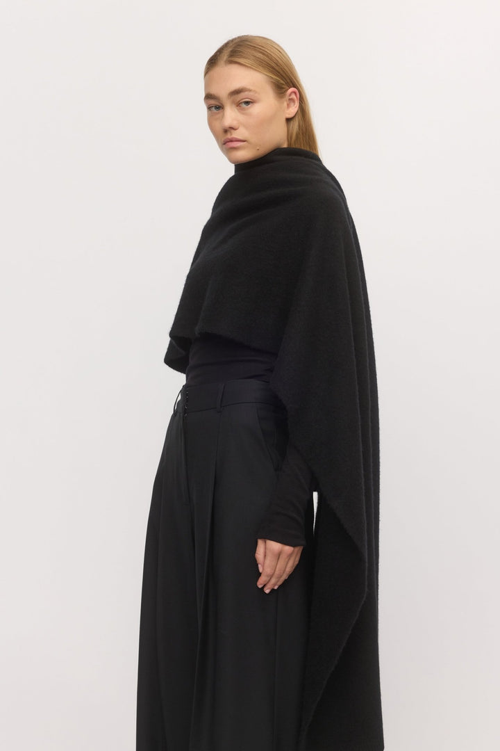 Side angle of woman in Brushed Anywhere Wrap Midnight – luxuriously brushed wool-cashmere wrap styled over a black outfit.