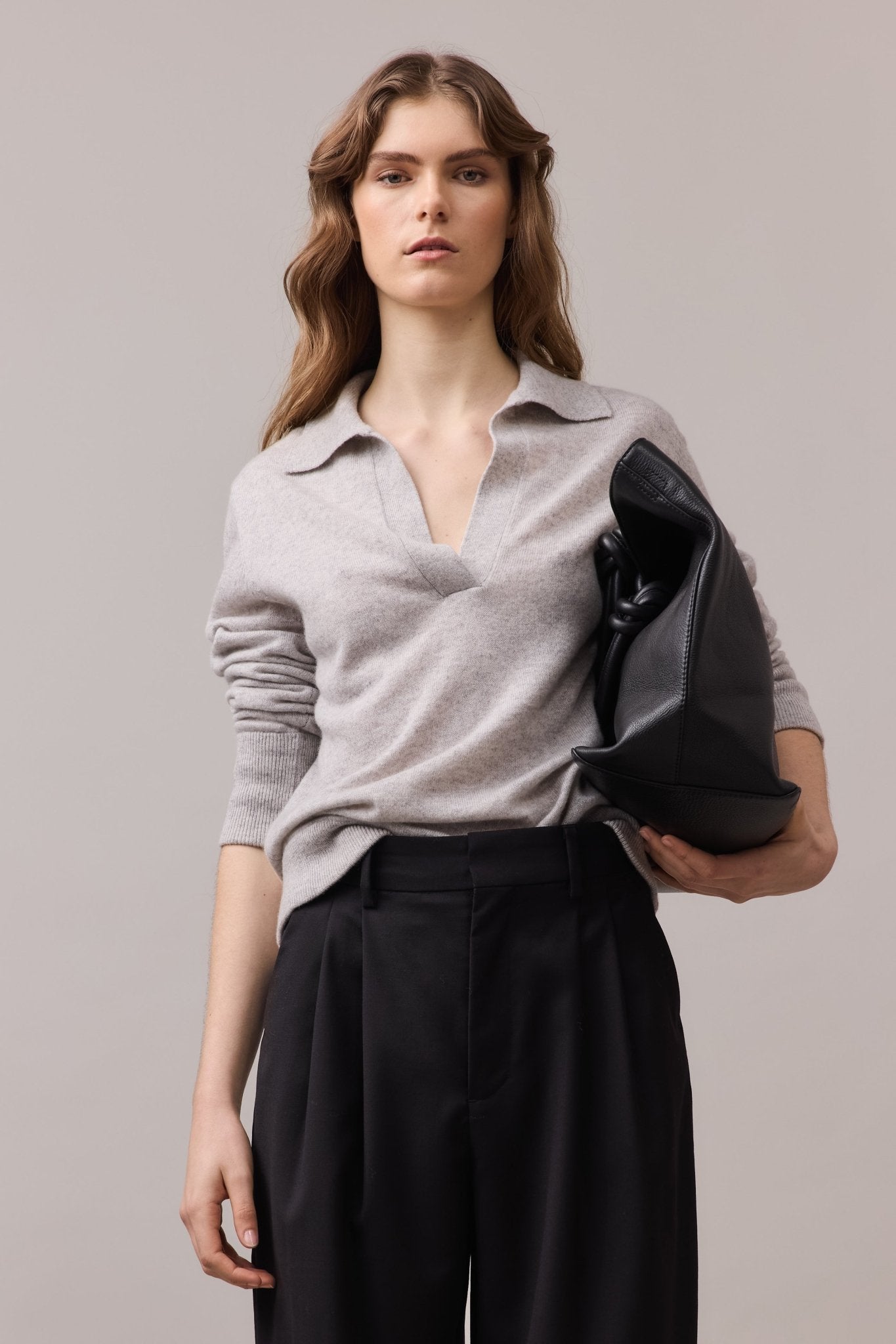 Close-up of the woman wearing the greycast Cashmere Polo Knit, sleeves rolled up and tucked into black wide-leg pants. The soft cashmere material and relaxed fit of the polo are highlighted, showcasing the elegant design.