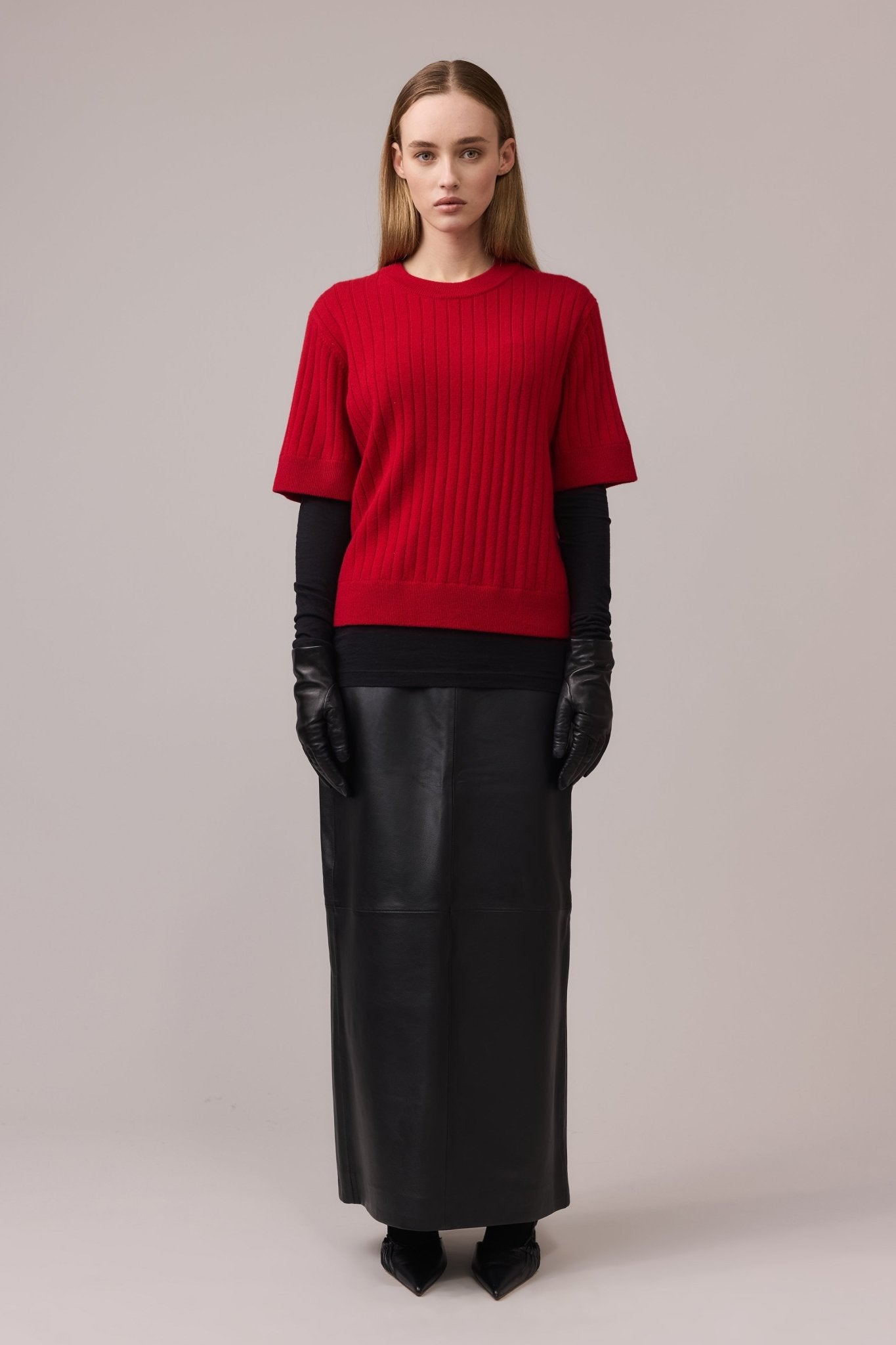Woman wearing a cashmere short-sleeve ribbed tee paired with a leather maxi skirt, black shirt underneath, and leather gloves for an elevated look.