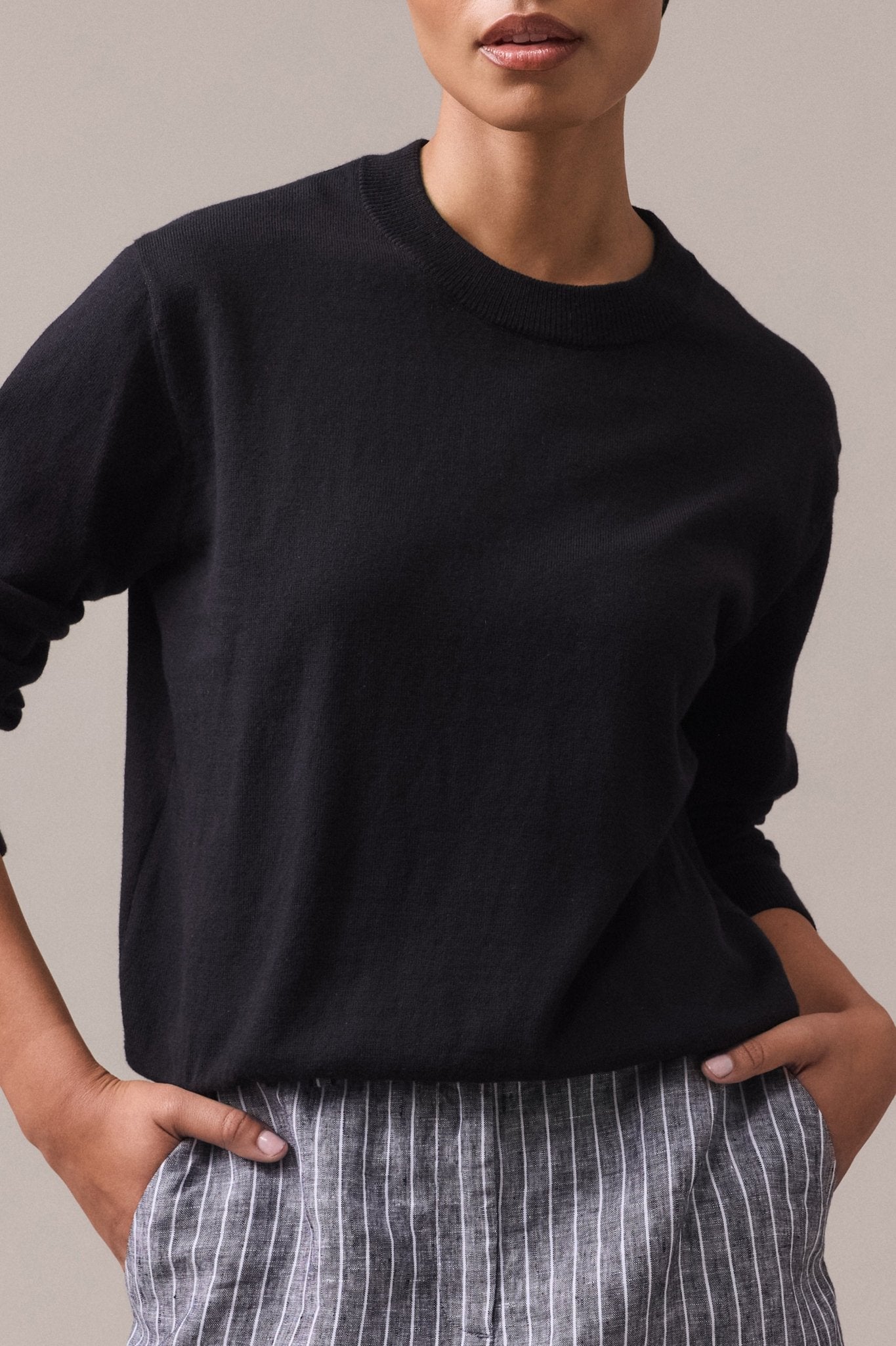 A woman wearing a black cotton-cashmere crew neck knit with long sleeves.