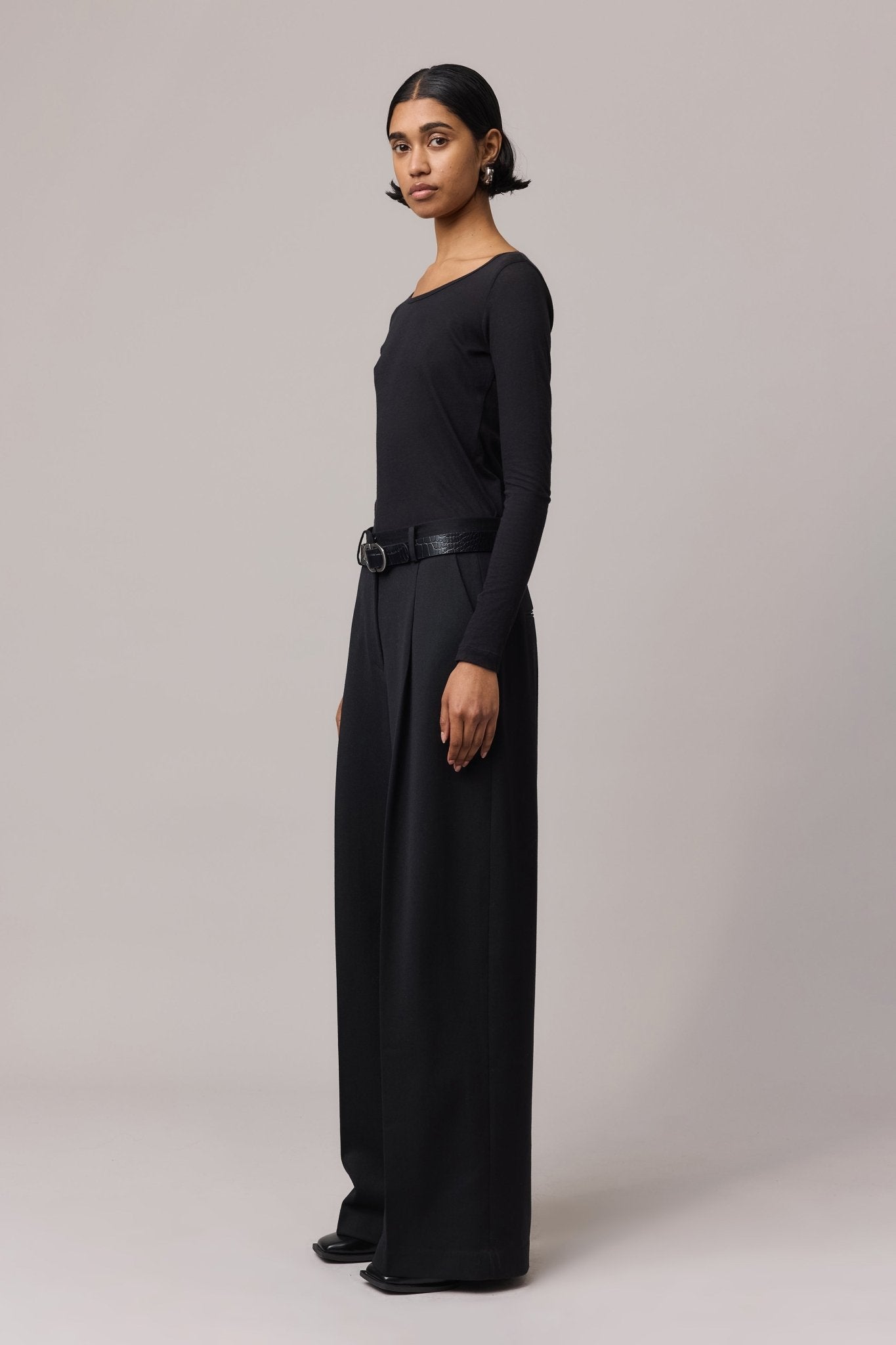 Side view of the black semi-sheer top, showing its fitted silhouette and lightweight fabric.